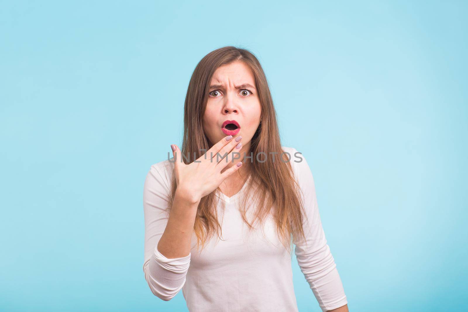 Concerned scared woman on blue background in studio