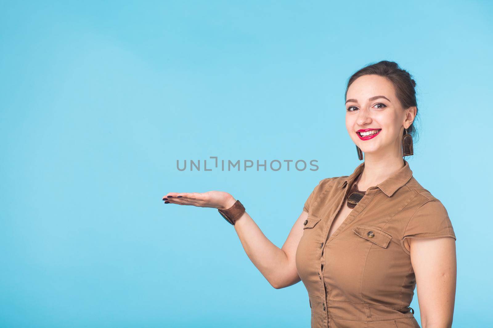 Portrait of young beautiful ginger woman with freckles cheerfuly smiling looking at camera. Isolated on pastel blue background. Copy space.