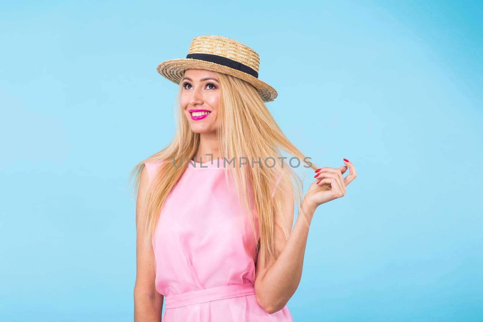 beauty fashion summer portrait of blonde woman with red lips and pink dress on blue background with copy space.