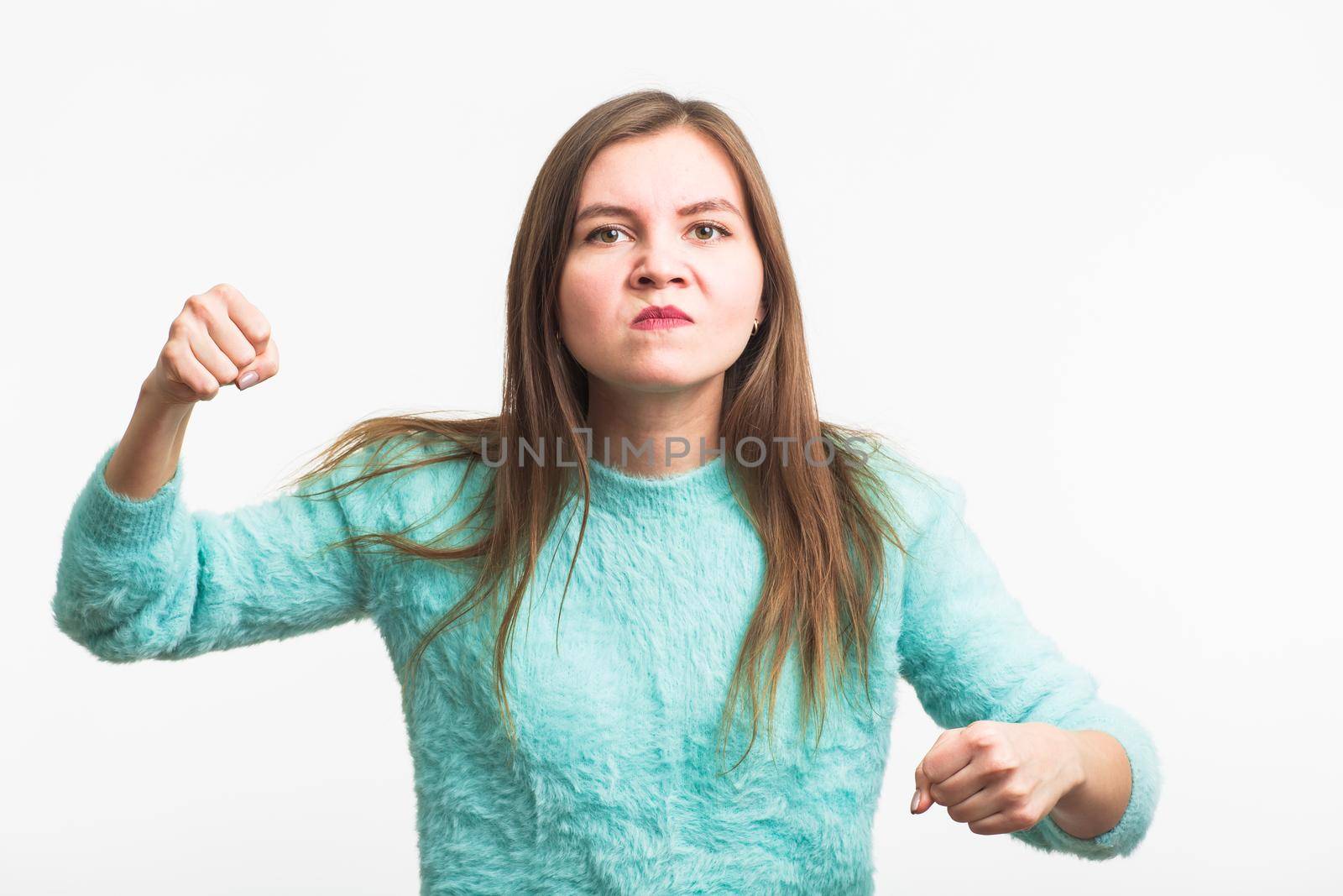 Angry aggressive woman with ferocious expression on white background.