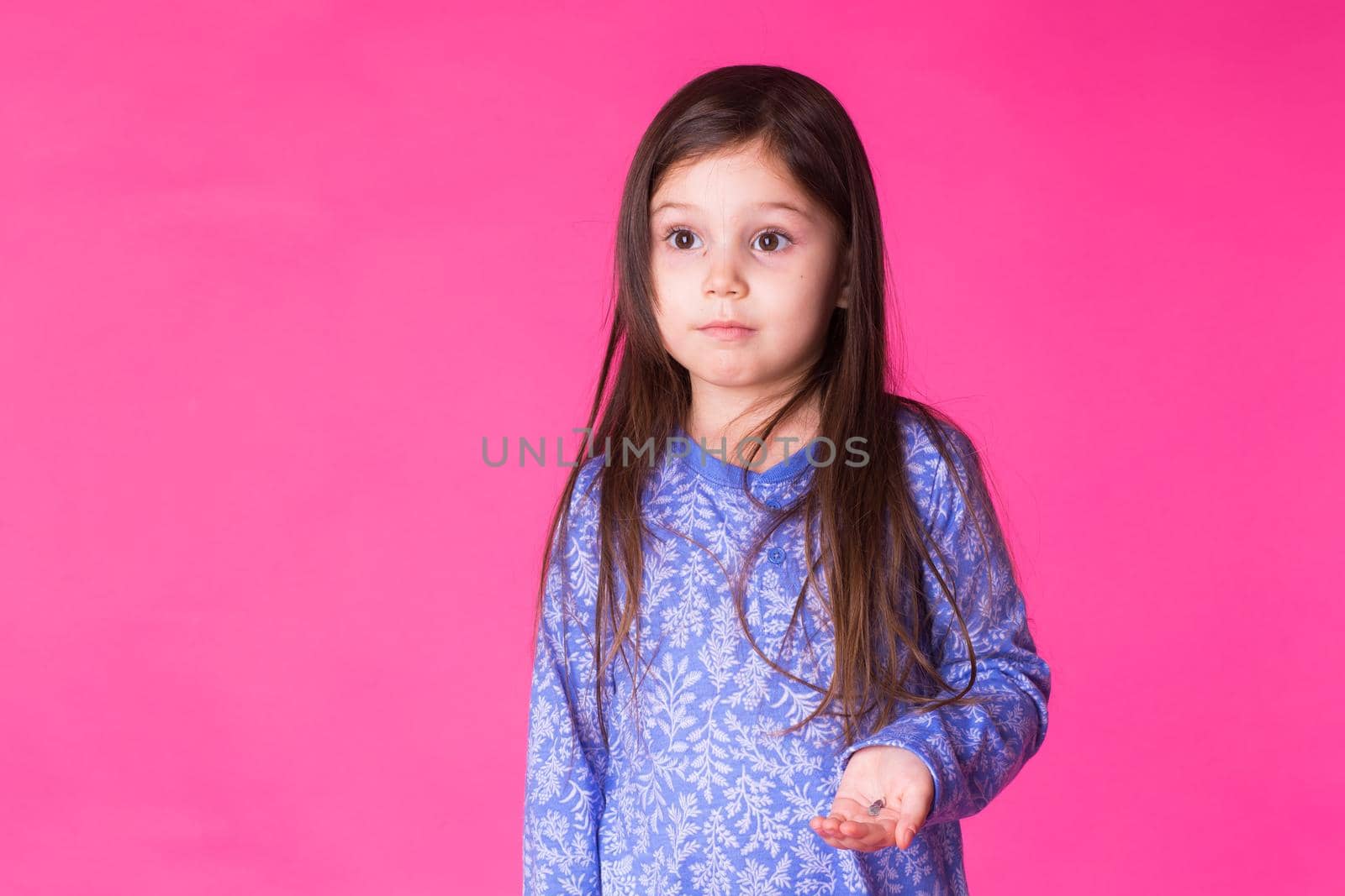 Portrait of adorable little girl isolated on a pink background.