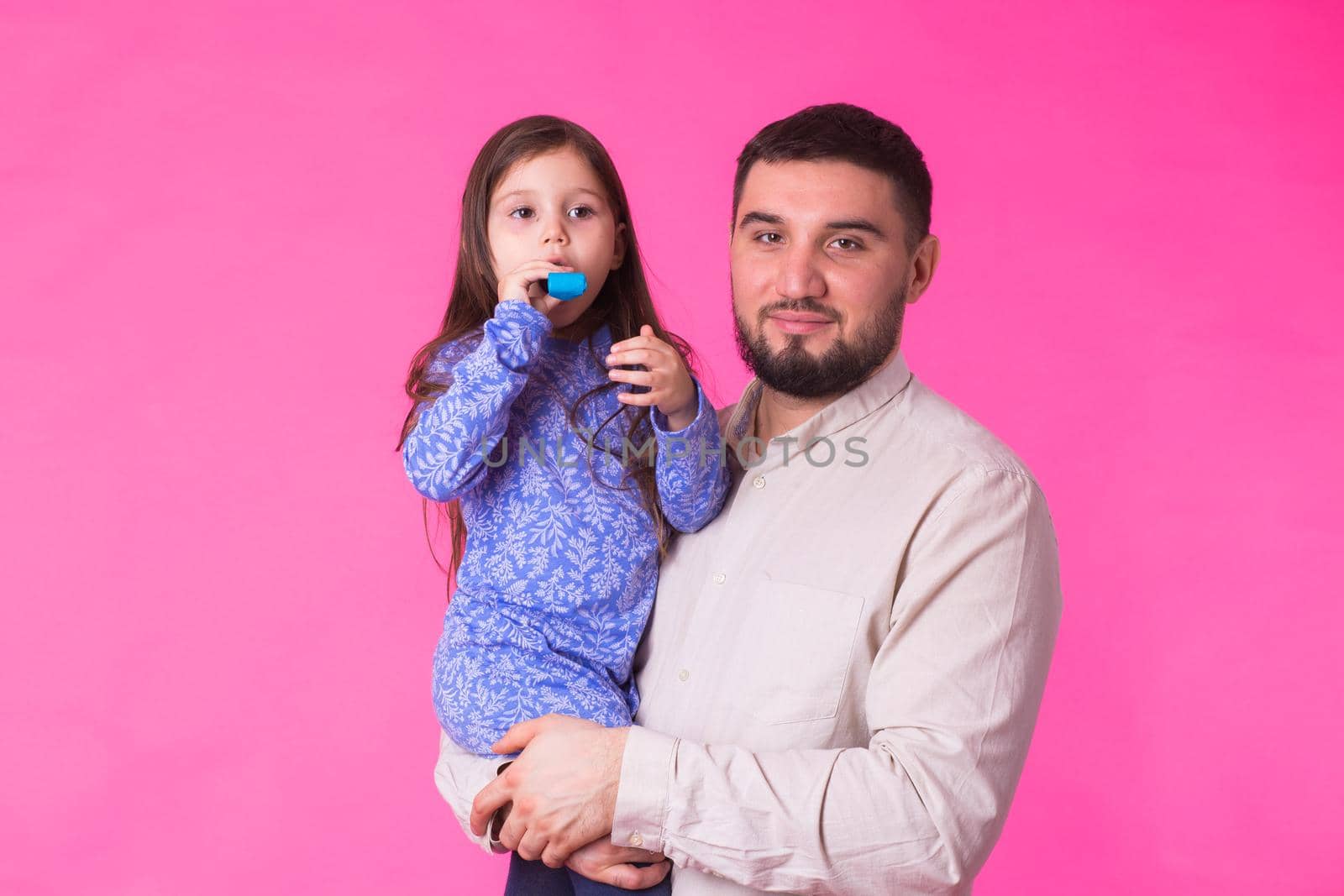 Happy father holding baby daughter in hands over pink background.