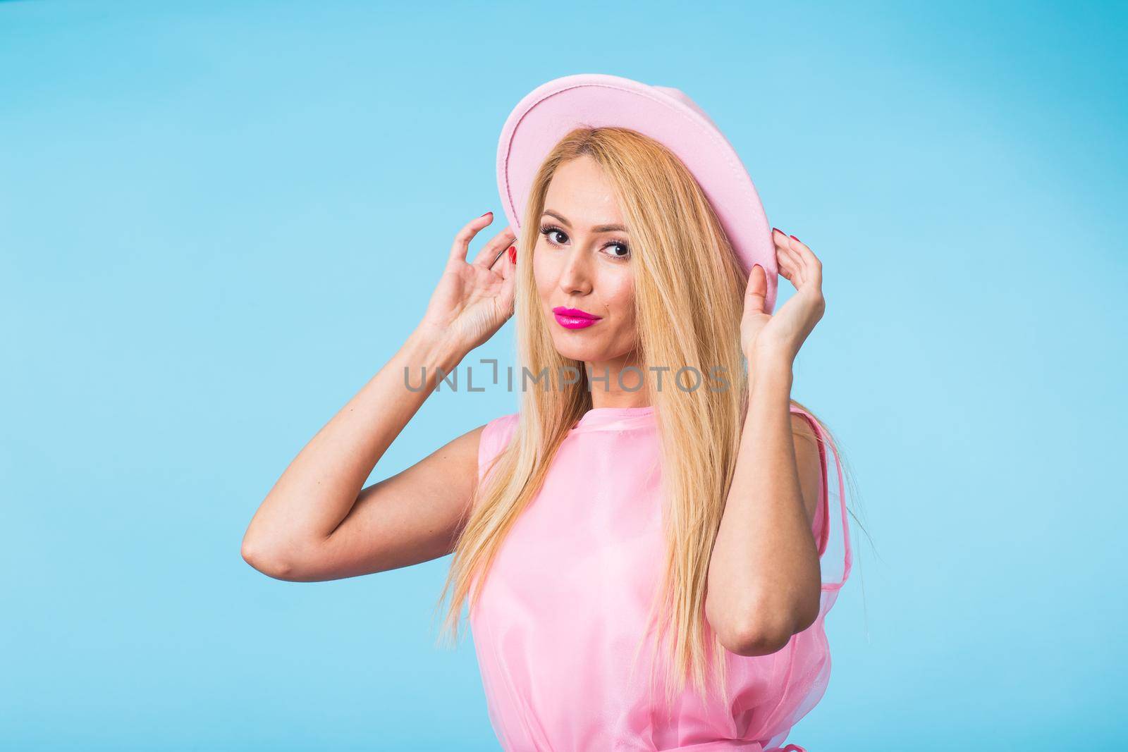 Beautiful woman with long straight blond hair. Fashion model posing at studio on blue background by Satura86