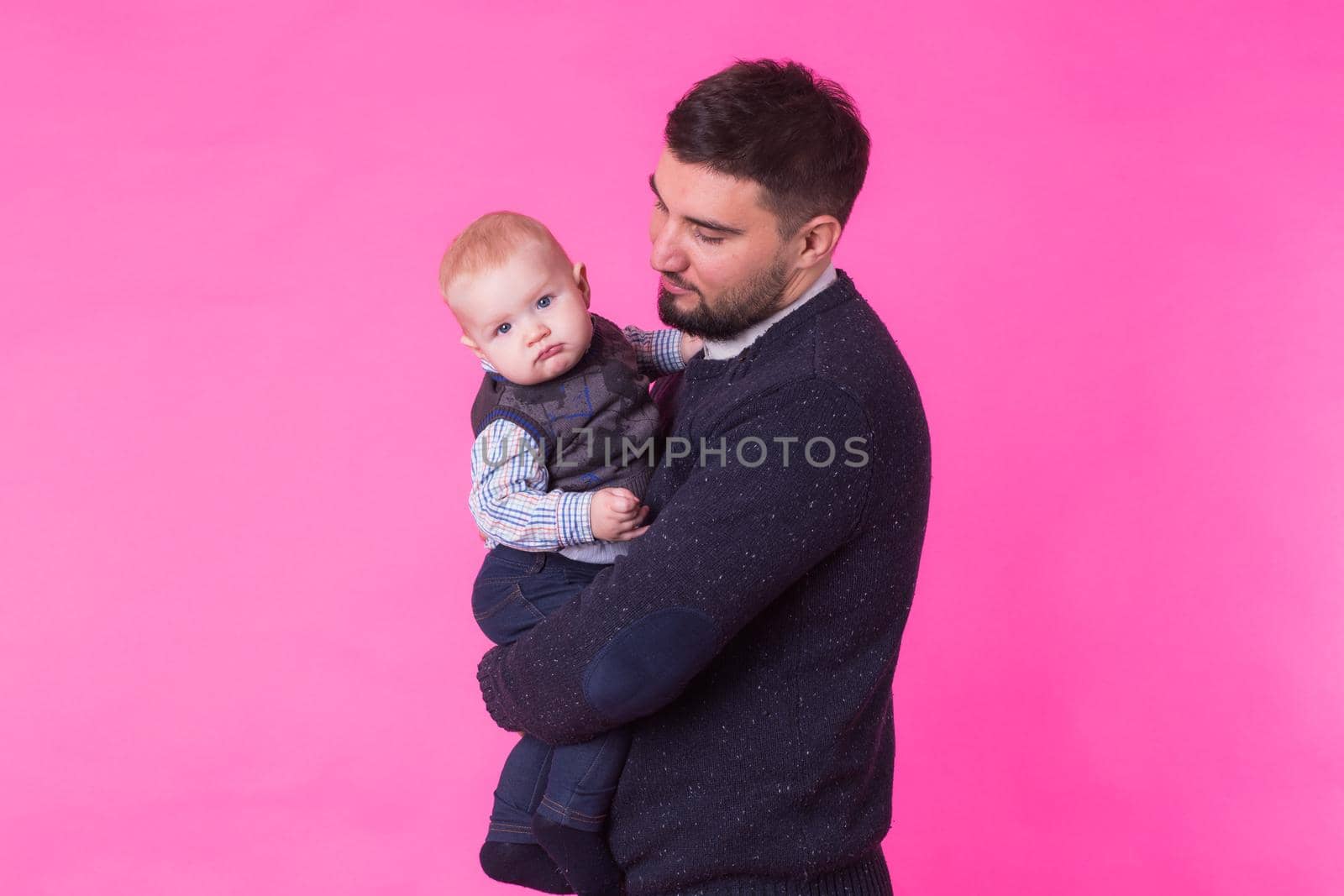 happy father with a baby son isolated on a pink background.