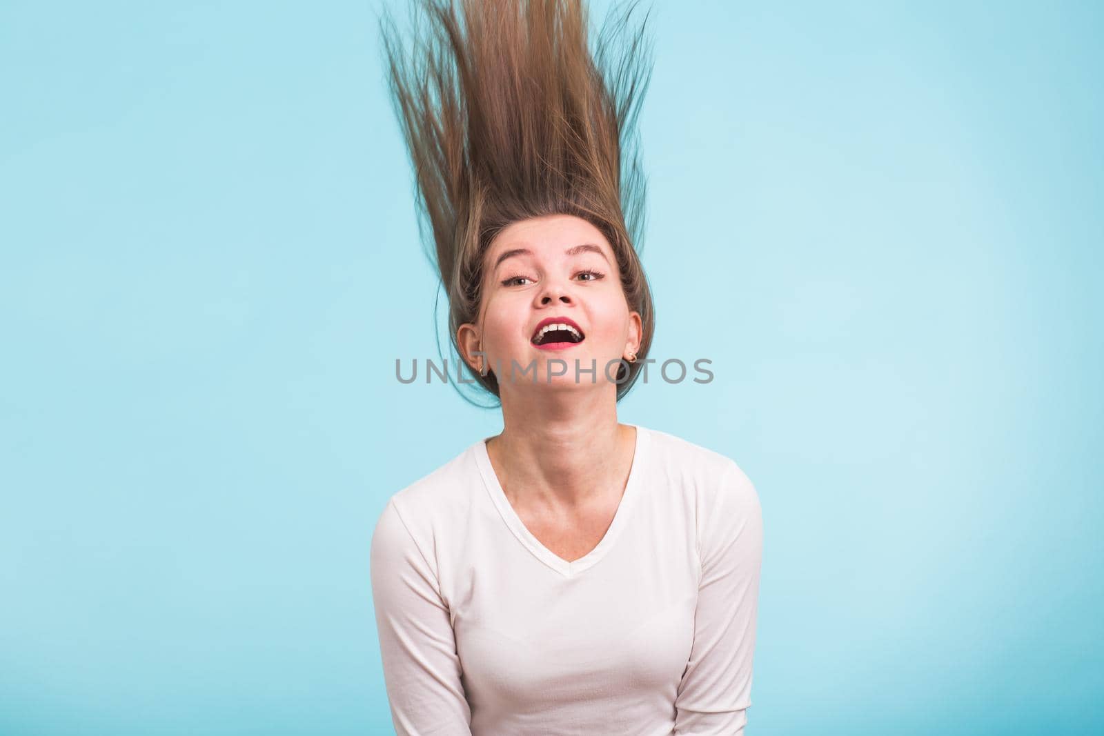 Portrait of a beautiful girl with flying hair on blue background.
