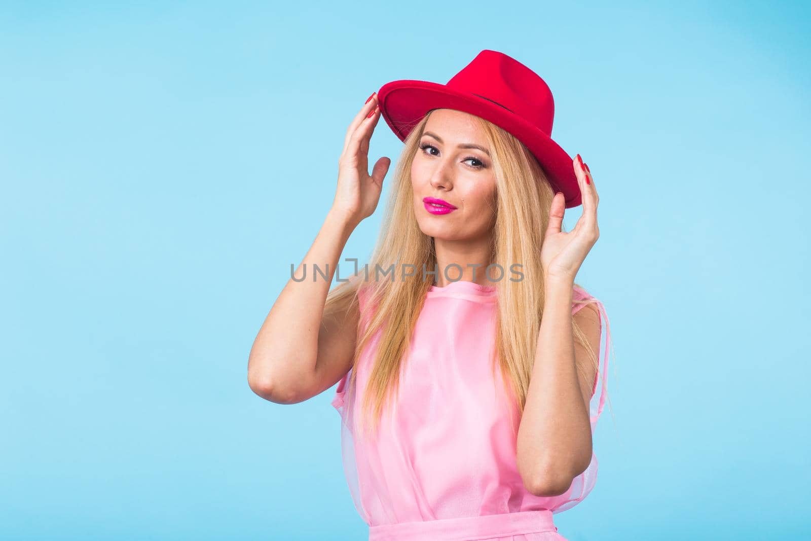 beauty fashion summer portrait of blonde woman with red lips and pink dress on blue background with copy space by Satura86