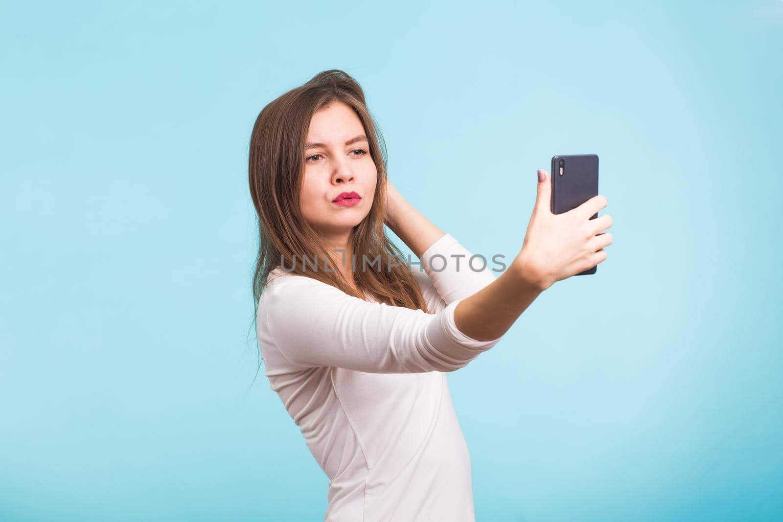 Joyful young women making selfie by her smart phone on blue background by Satura86