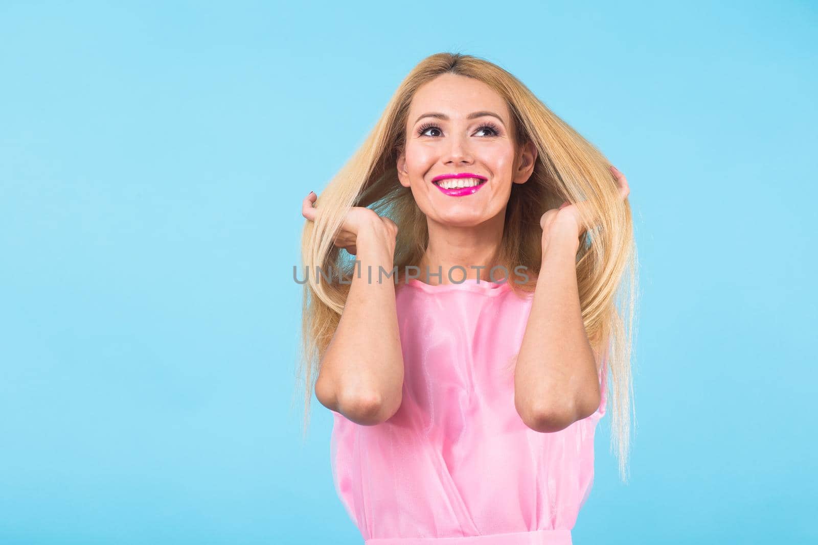 Portrait of smiling blonde woman in fashionable look on blue background. Style, fashion, summer and people concept.