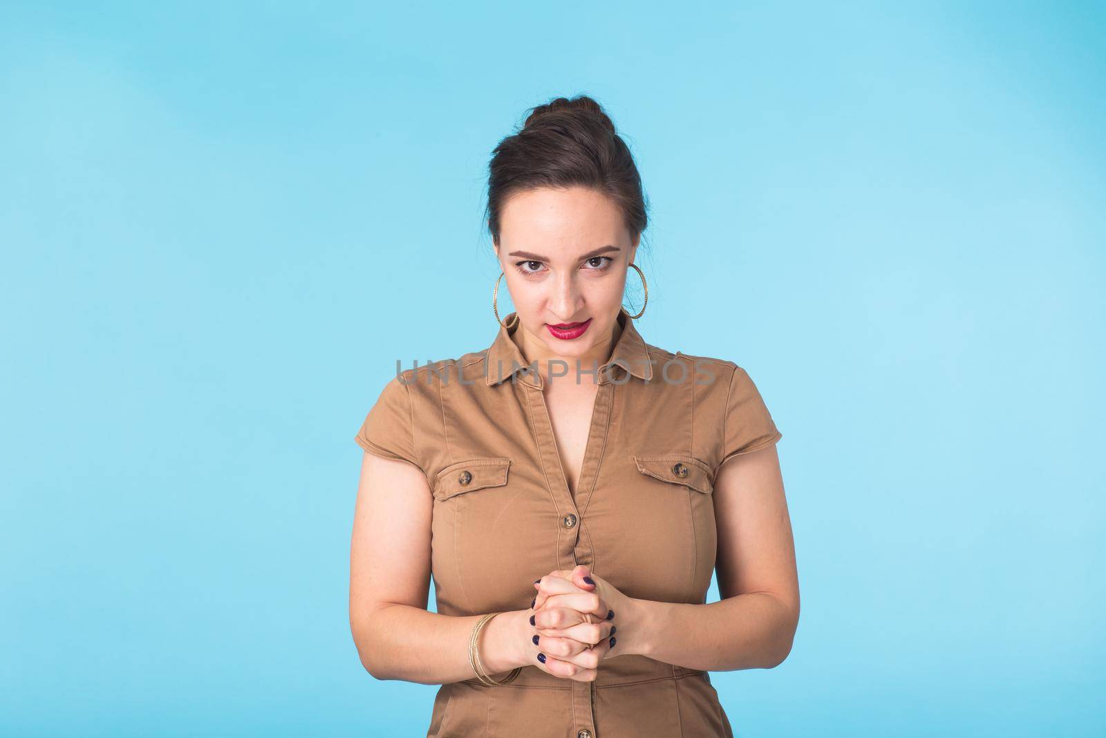 Angry aggressive woman with ferocious expression on blue background.