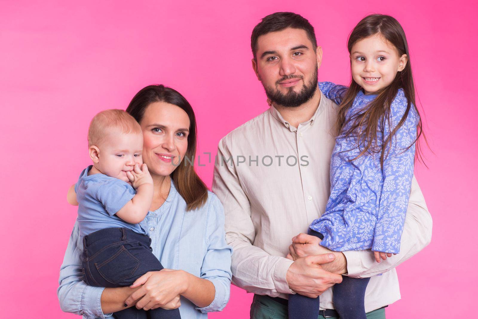 Cute family posing and smiling at camera together on pink background by Satura86