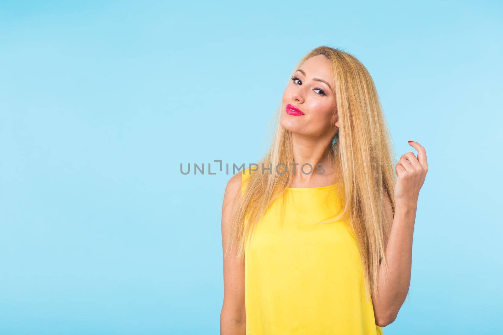 Portrait of happy cheerful smiling young beautiful blond woman on blue background.