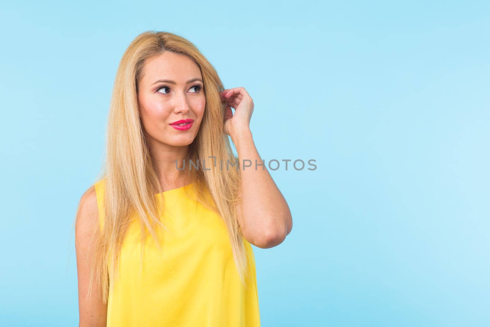 Portrait of smiling blonde woman in fashionable look on blue background. Style, fashion, summer and people concept.