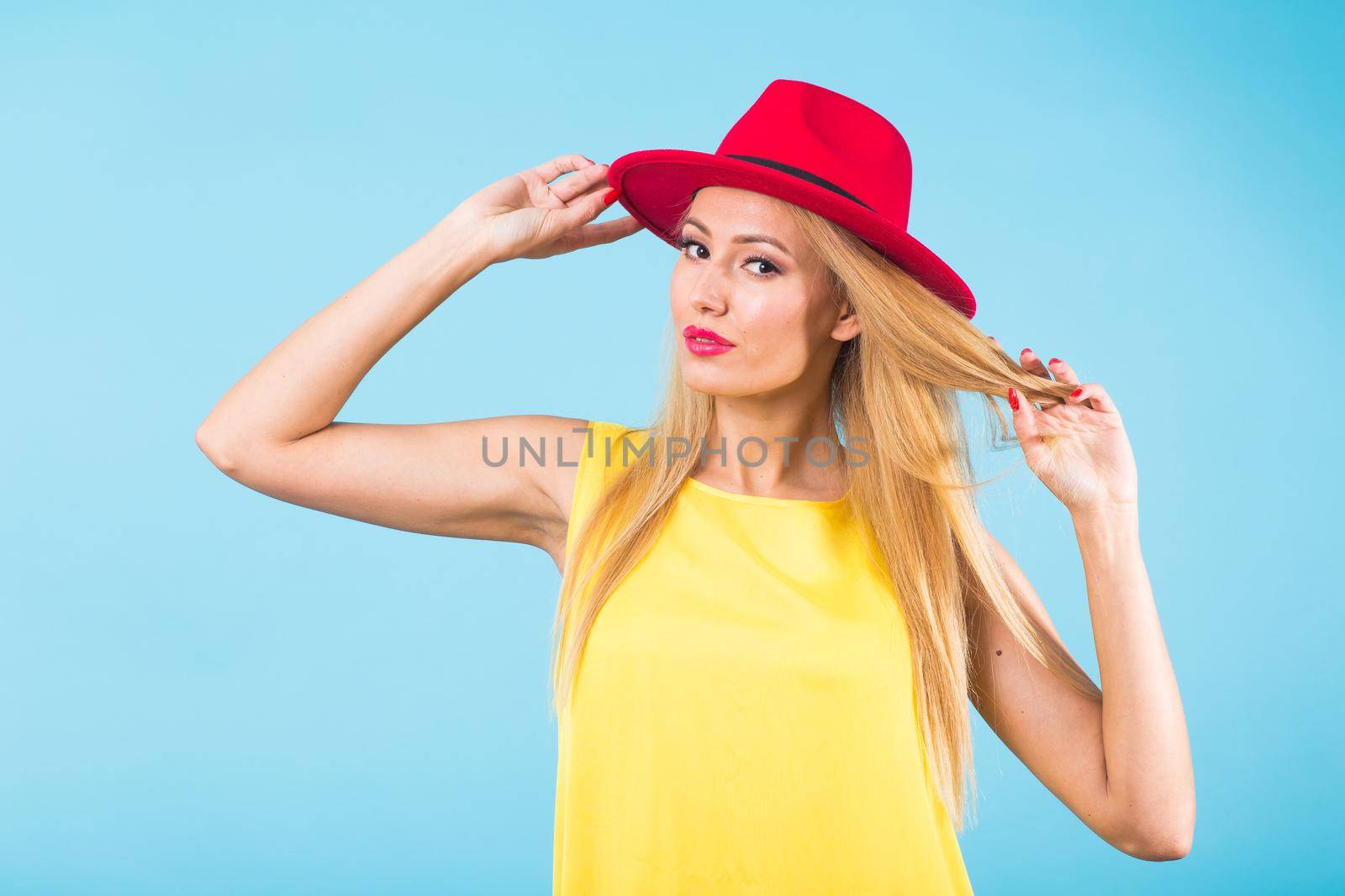 Beautiful woman with long straight blond hair. Fashion model posing at studio on blue background by Satura86