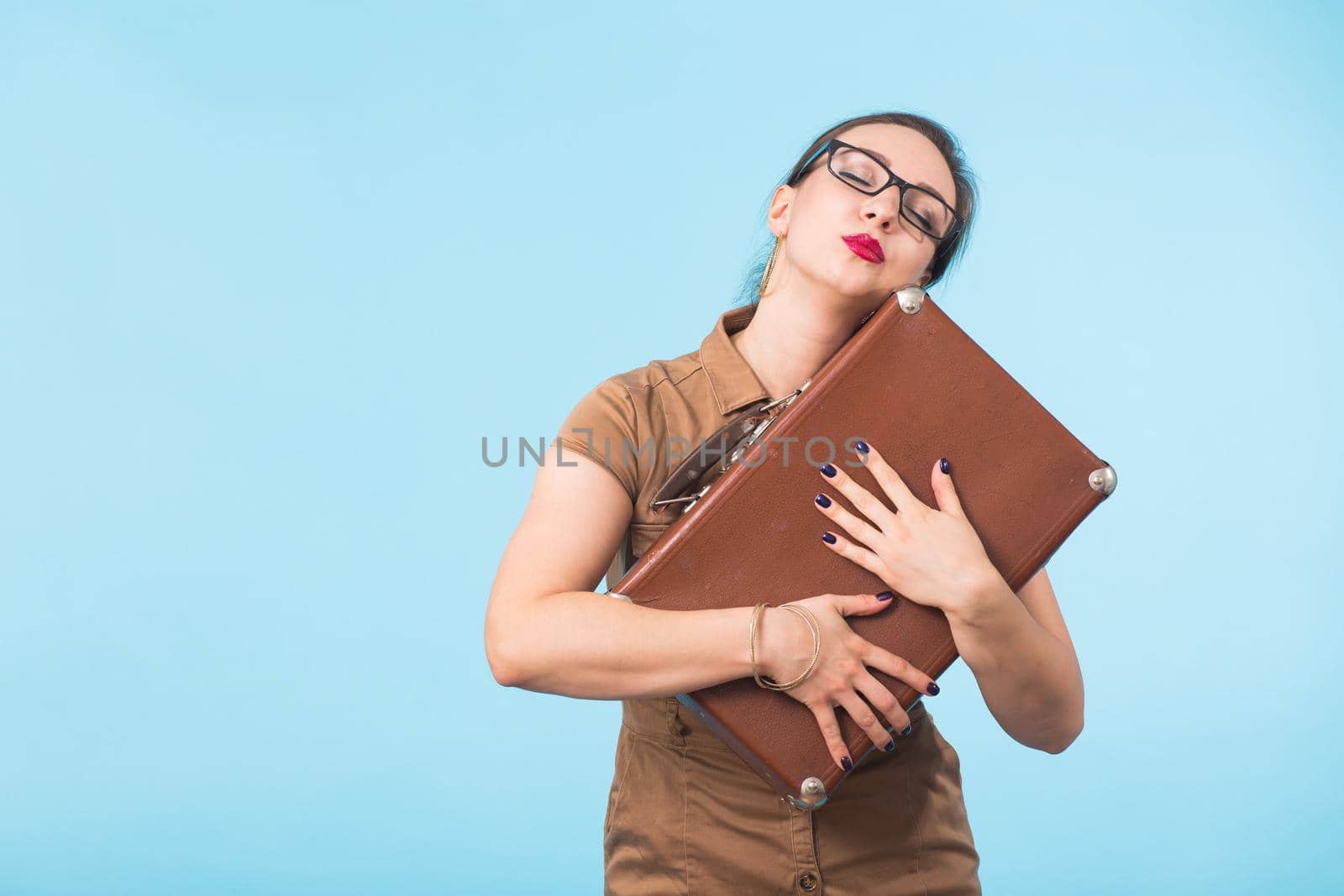 Portrait of excited young woman holding a suitcase isolated over blue background, Travel, holidays and vacation concept. by Satura86