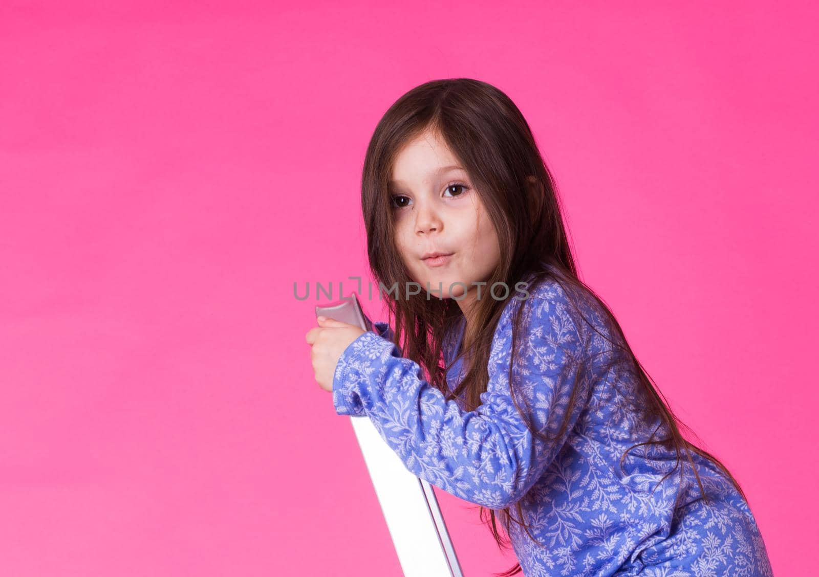 happy little girl on a folding ladder over pink background.