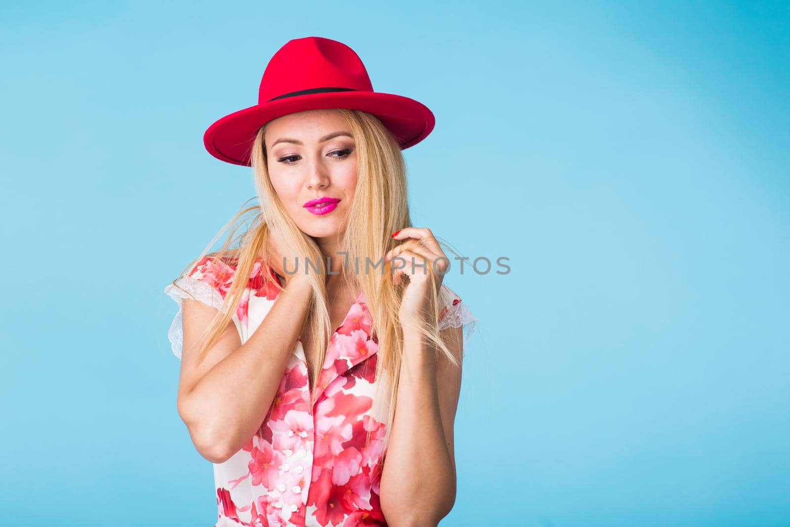 beauty fashion summer portrait of blonde woman with red lips and pink dress on blue background with copy space.