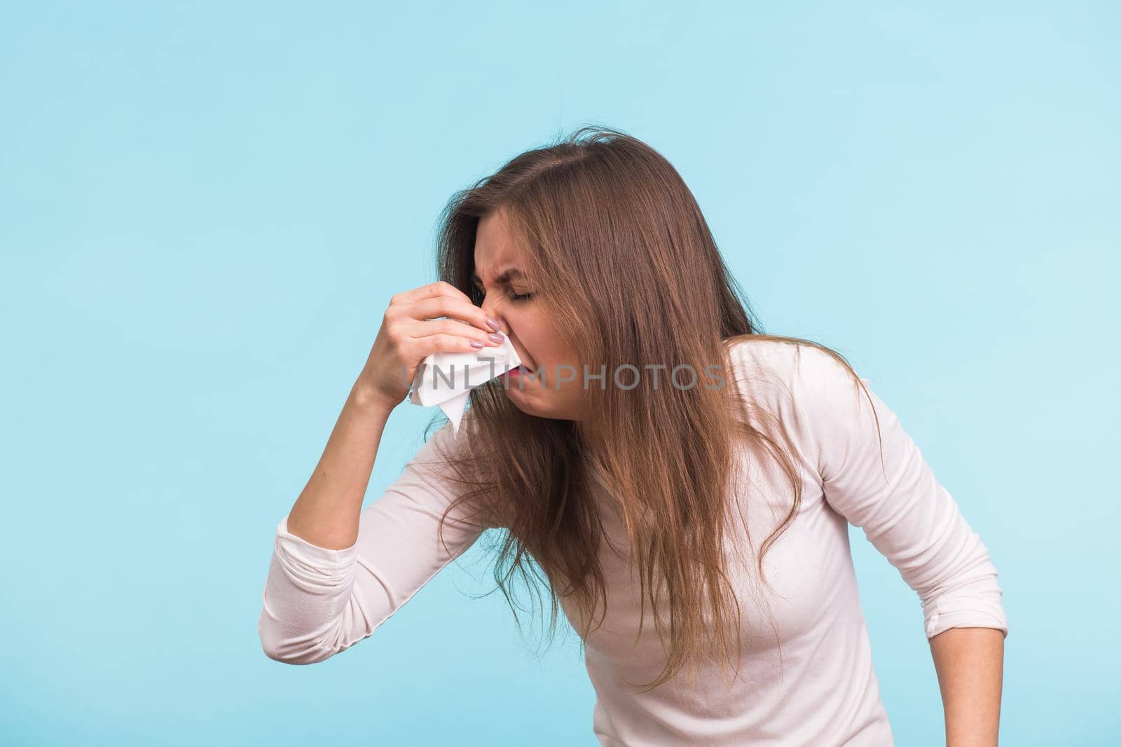 Young woman with handkerchief. Sick girl isolated has runny nose on blue background.