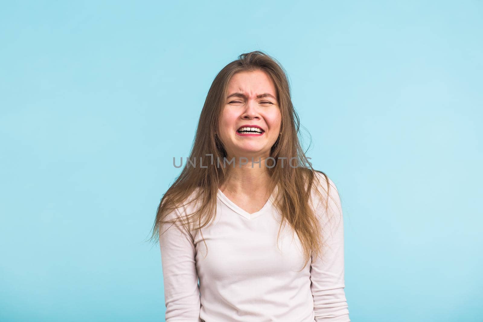 A sad beautiful woman crying on blue background