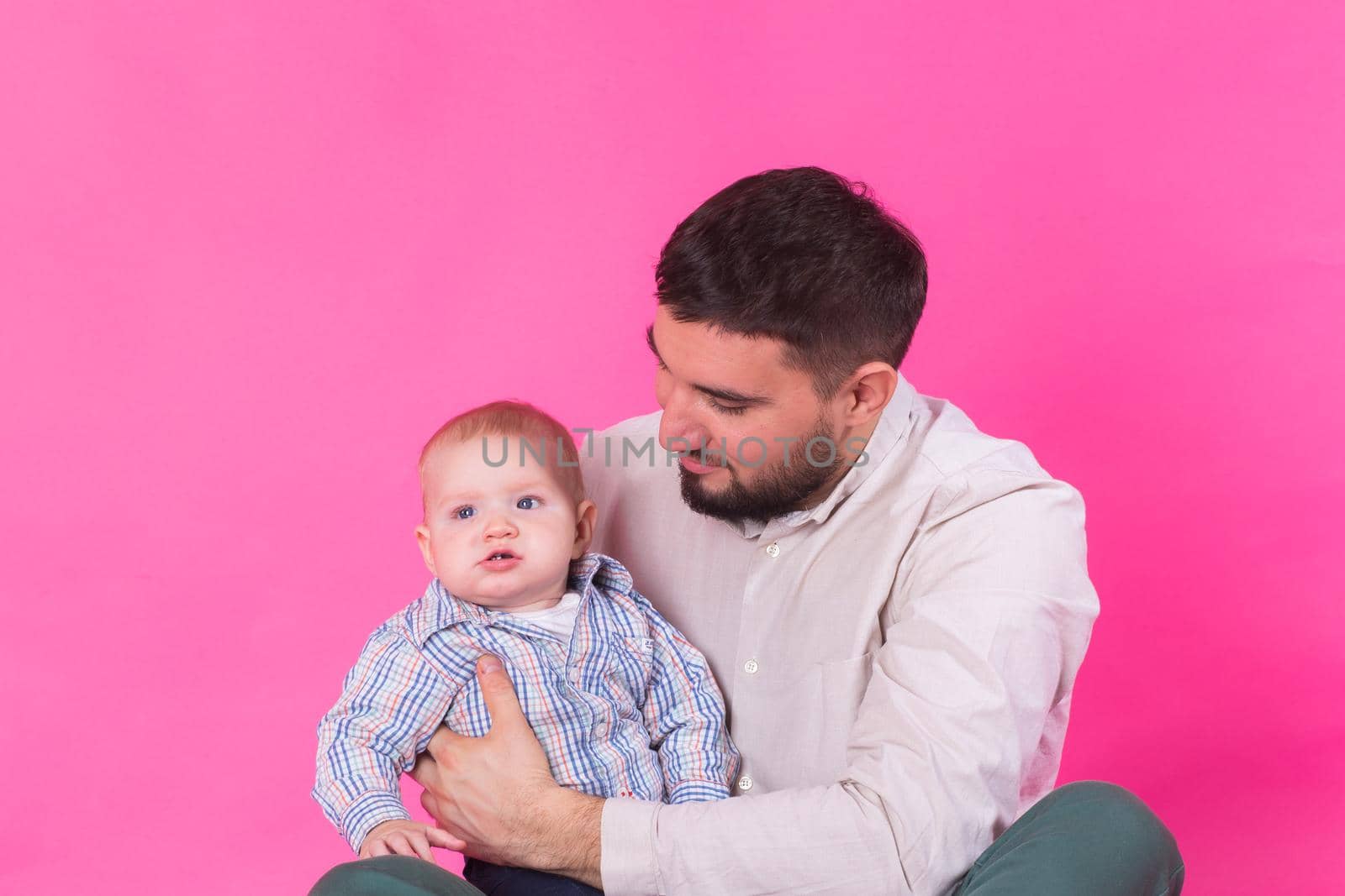 Happy portrait of the father and son on pink background. In studio by Satura86