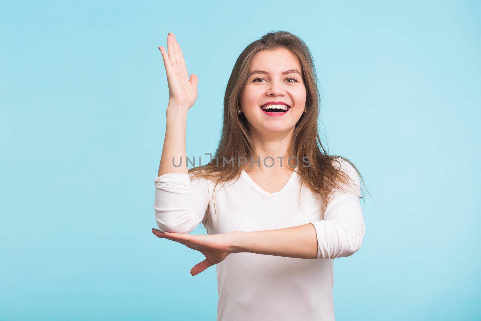 Beautiful caucasian student raising her hand knowing the answer. Isolated on blue.