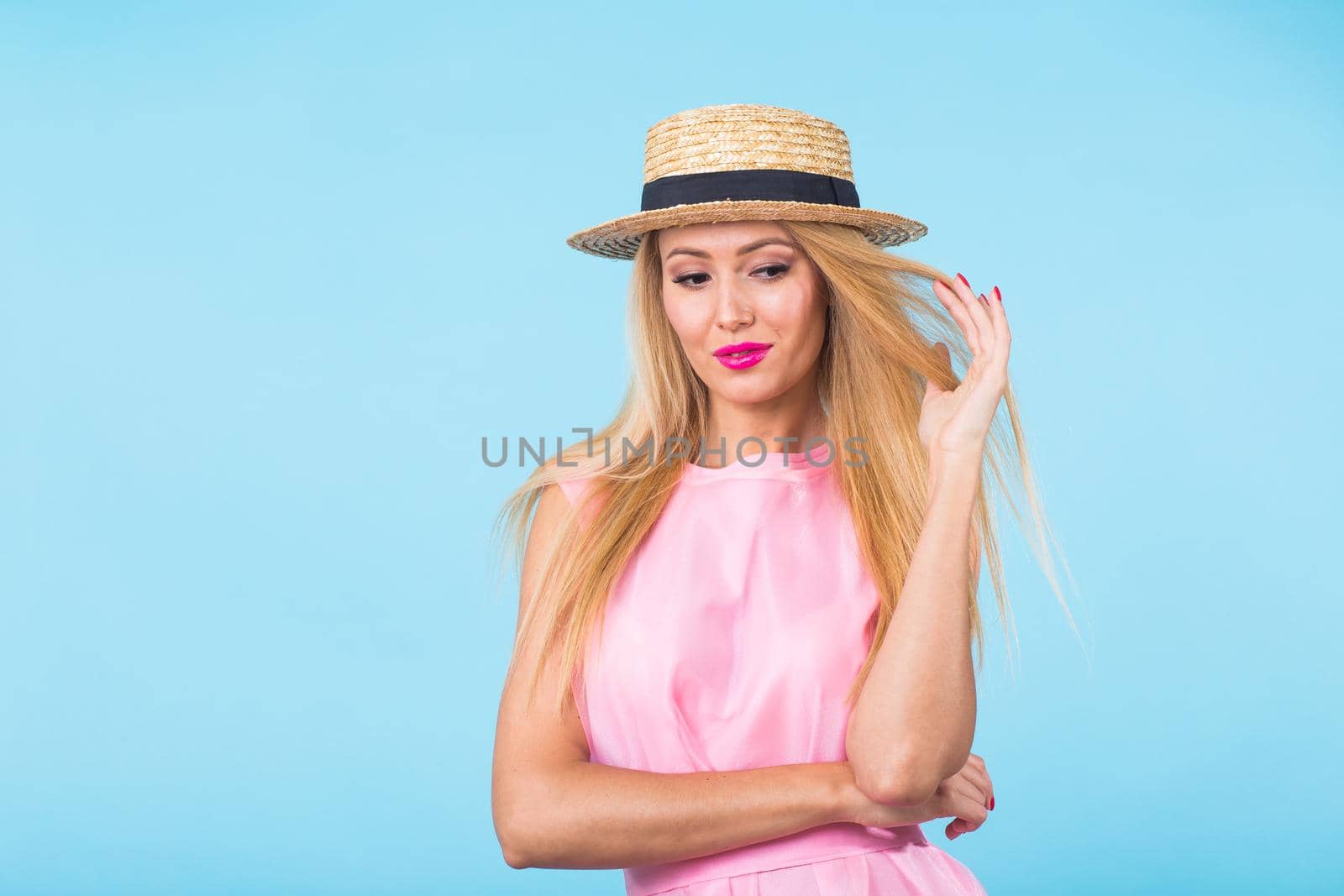 beauty fashion summer portrait of blonde woman with red lips and pink dress on blue background with copy space by Satura86