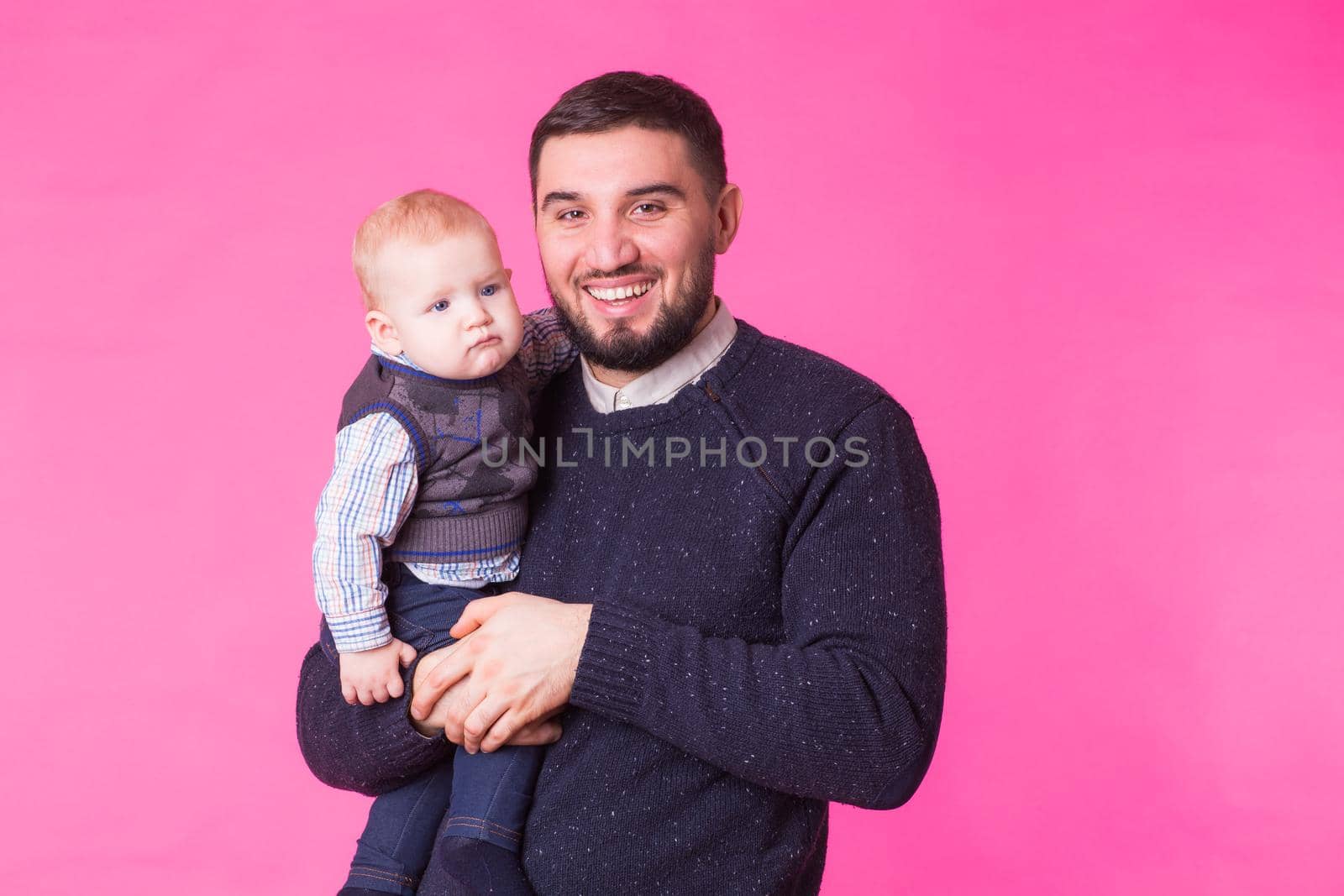 Happy father holding baby son in hands over pink background by Satura86