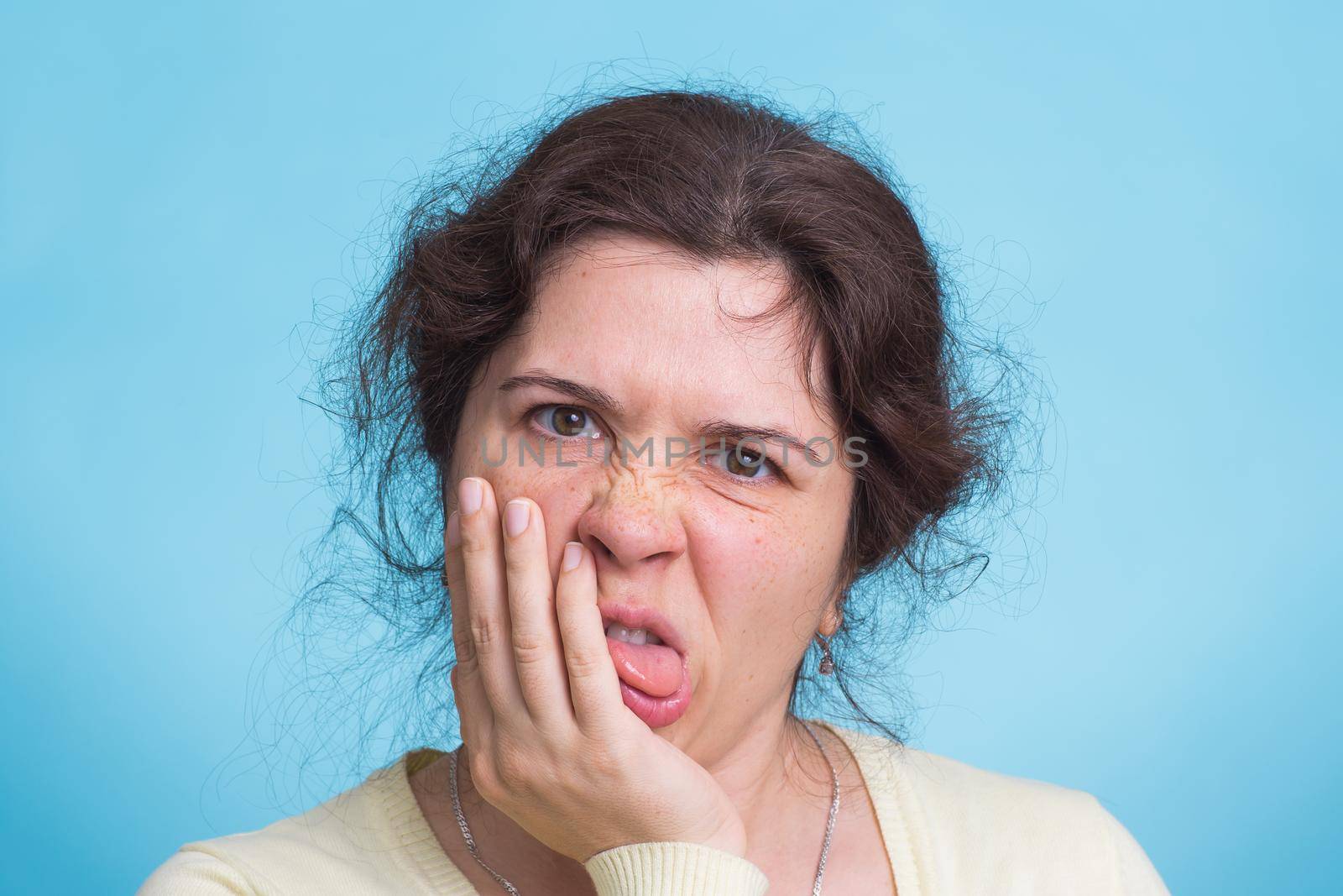 Concerned scared woman on blue background in studio