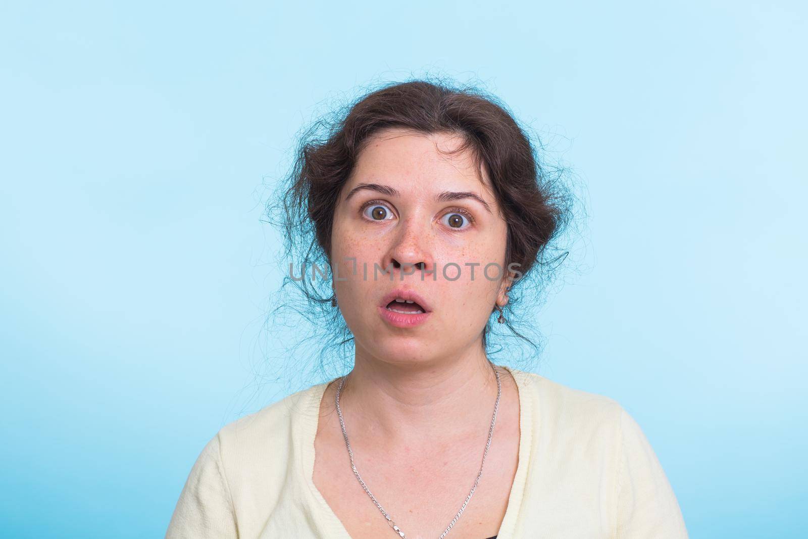 Concerned scared woman on blue background in studio