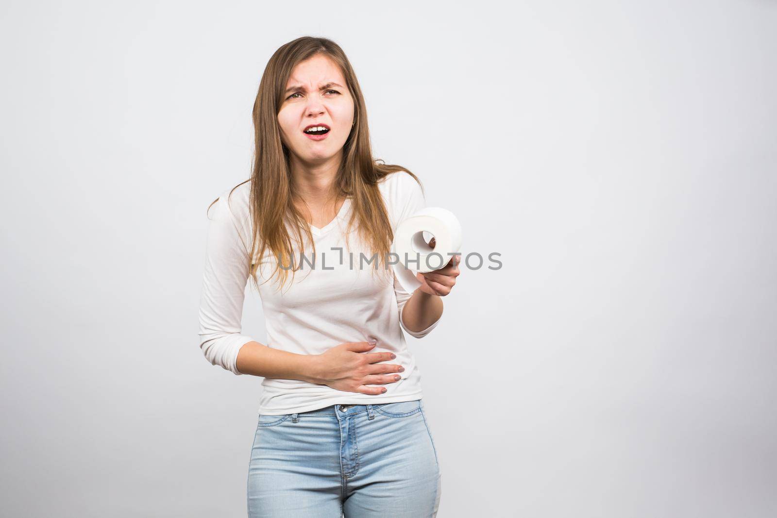 Sick woman with hands pressing her crotch lower abdomen, holding paper roll. Medical problems, incontinence, health care concept by Satura86