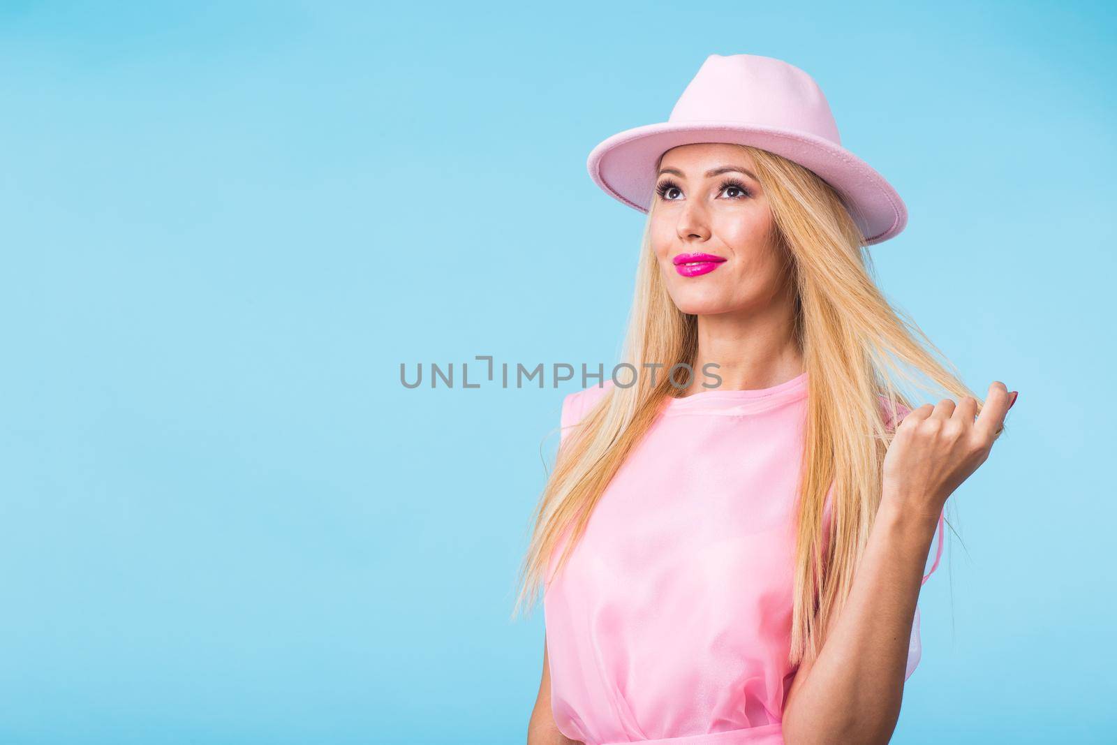 Beautiful woman with long straight blond hair. Fashion model posing at studio on blue background with copyspace by Satura86