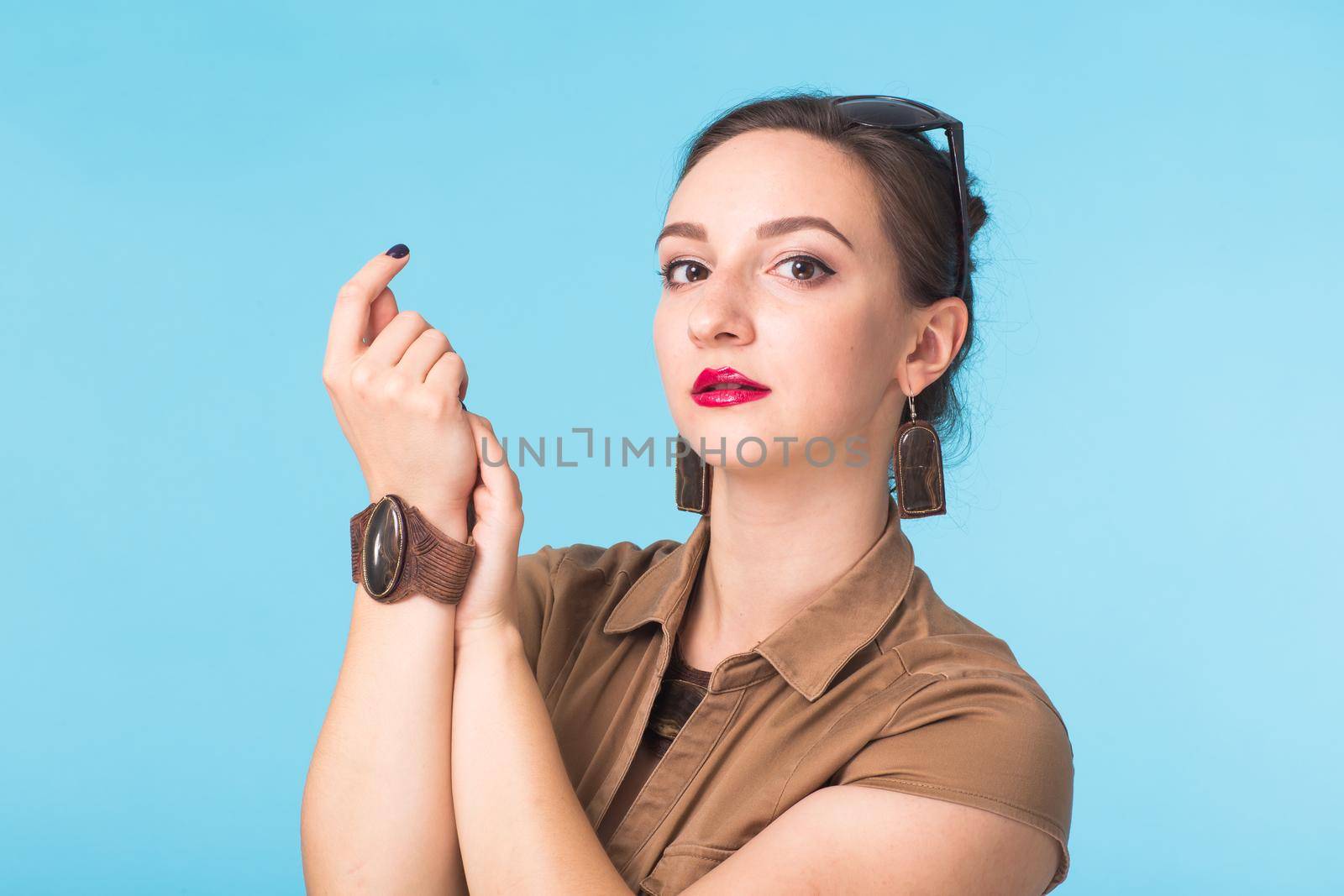 Portrait of young beautiful ginger woman with freckles cheerfuly smiling looking at camera. Isolated on pastel blue background. Copy space.