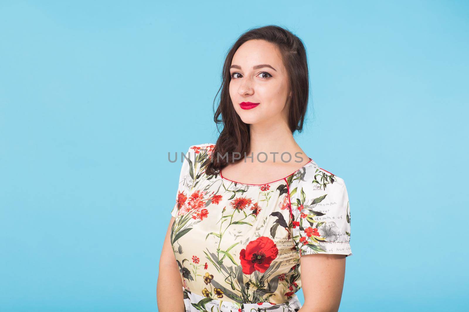 Portrait of young beautiful ginger woman with freckles cheerfuly smiling looking at camera. Isolated on pastel blue background. Copy space.