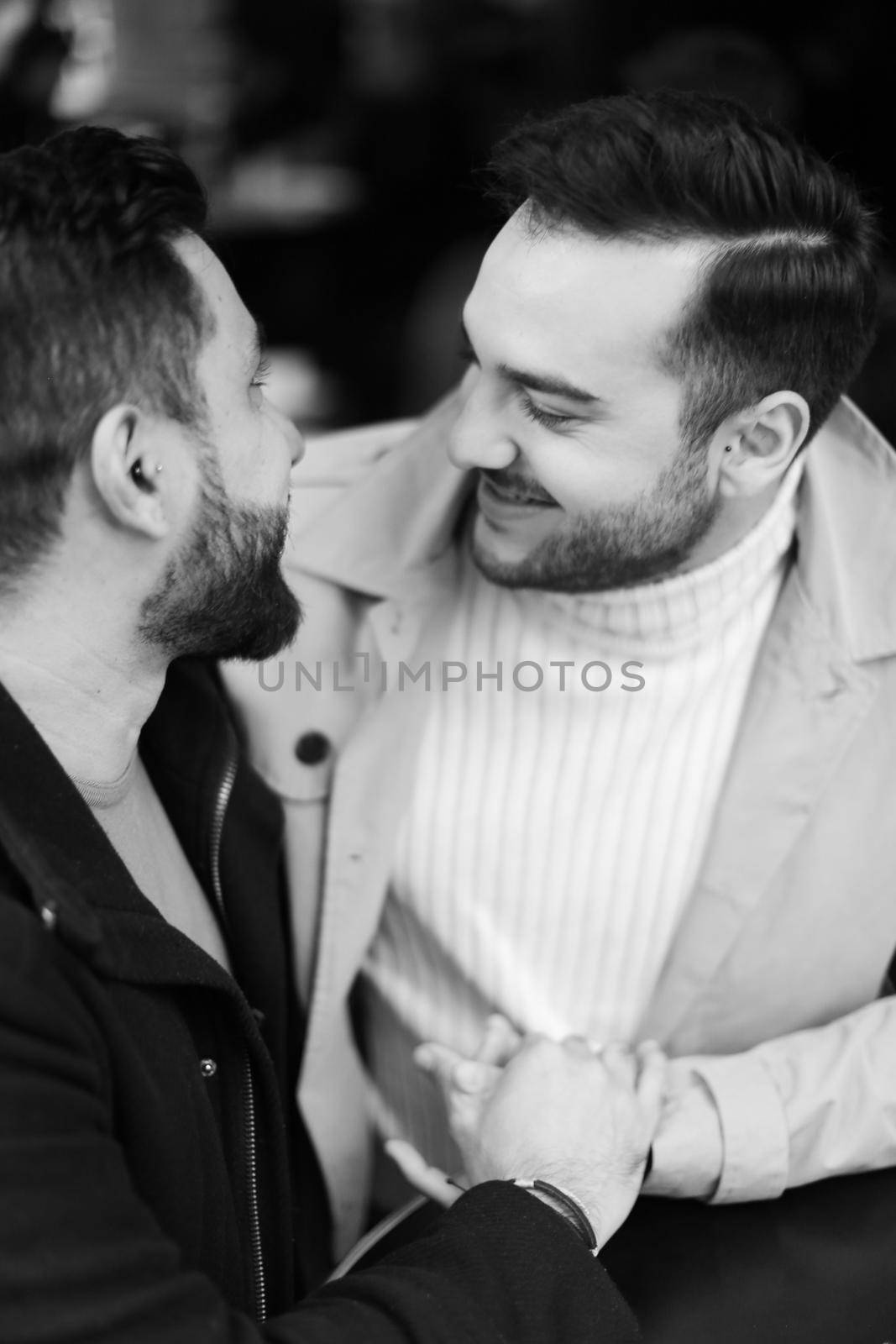 Black and white photo of young gays talking and holding hands. Concept of same sex couple and lgbt.