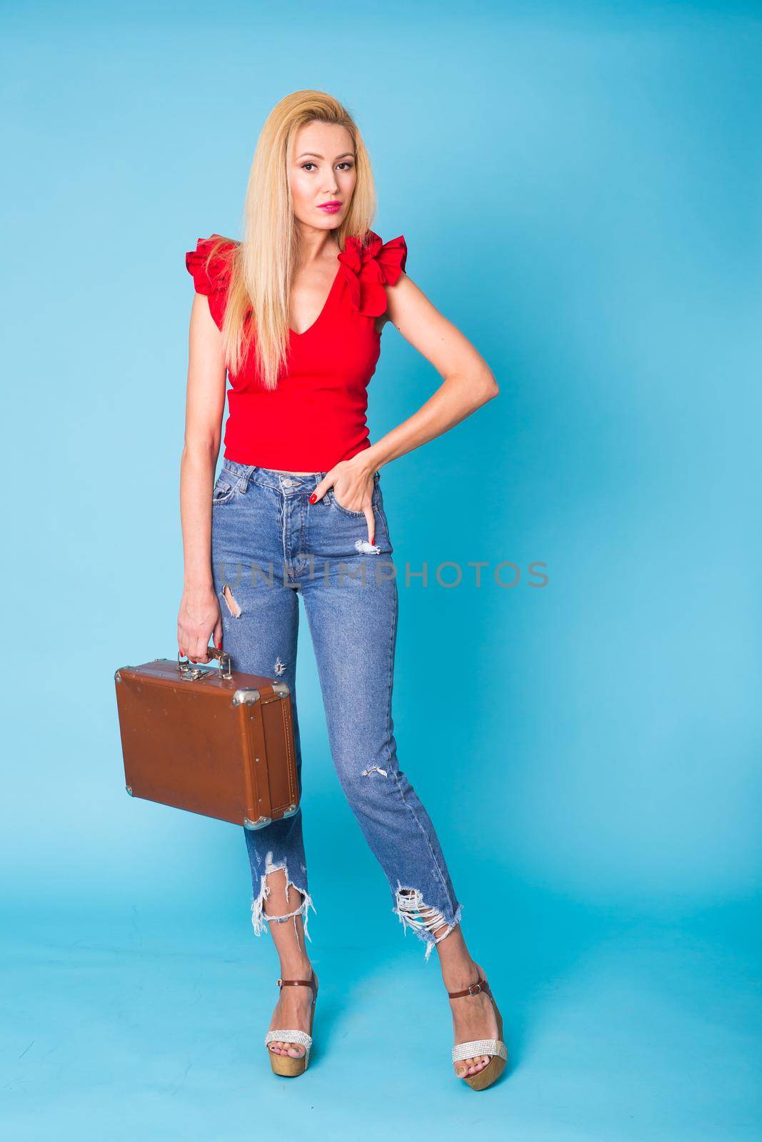 Summer, travel, people and holidays concept - fashionable young blond woman with retro suitcase isolated on blue background by Satura86