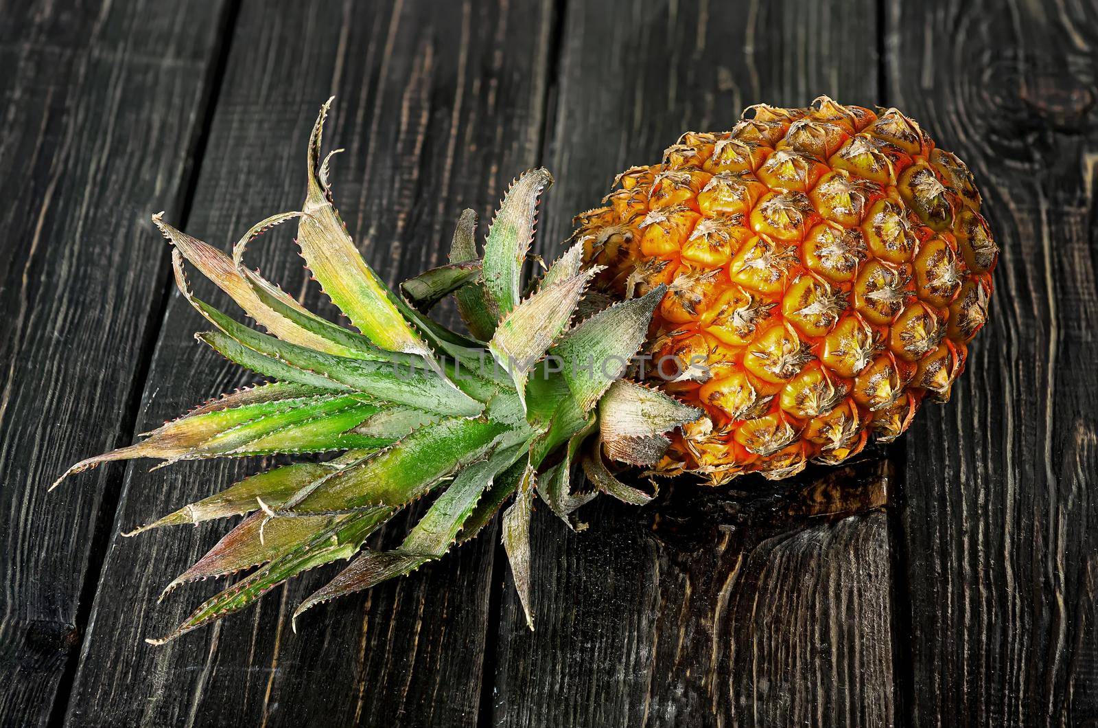 Ripe pineapple lies on a wooden table top view