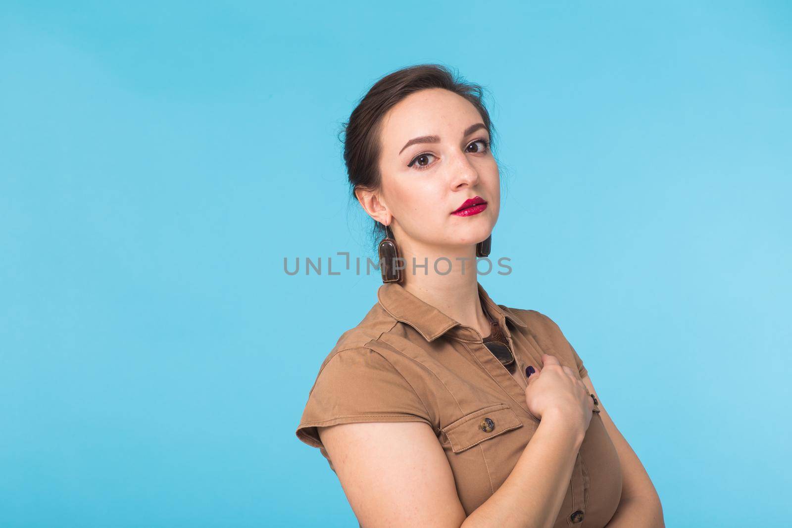 Portrait of young beautiful ginger woman with freckles cheerfuly smiling looking at camera. Isolated on pastel blue background. Copy space.