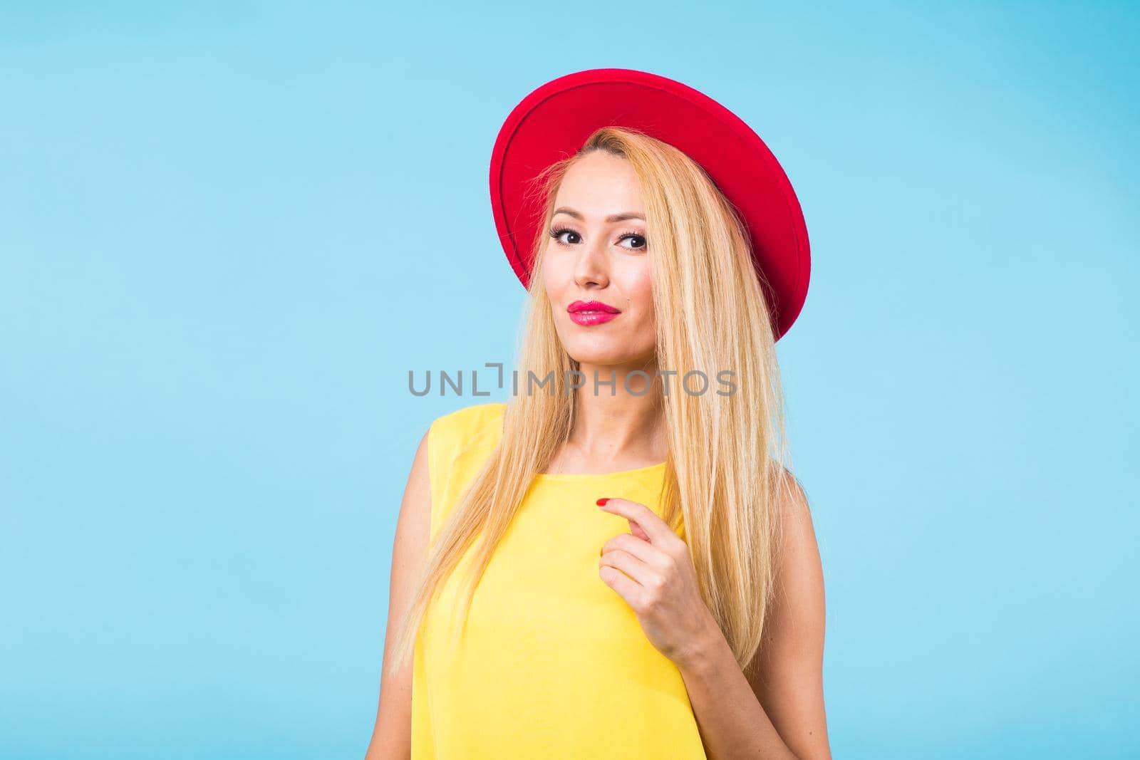 Portrait of happy cheerful smiling young beautiful blond woman on blue background.