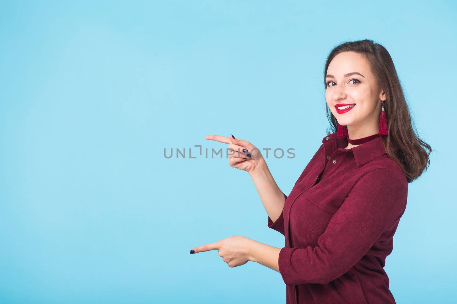 Portrait of young beautiful ginger woman with freckles cheerfuly smiling looking at camera. Isolated on pastel blue background. Copy space.