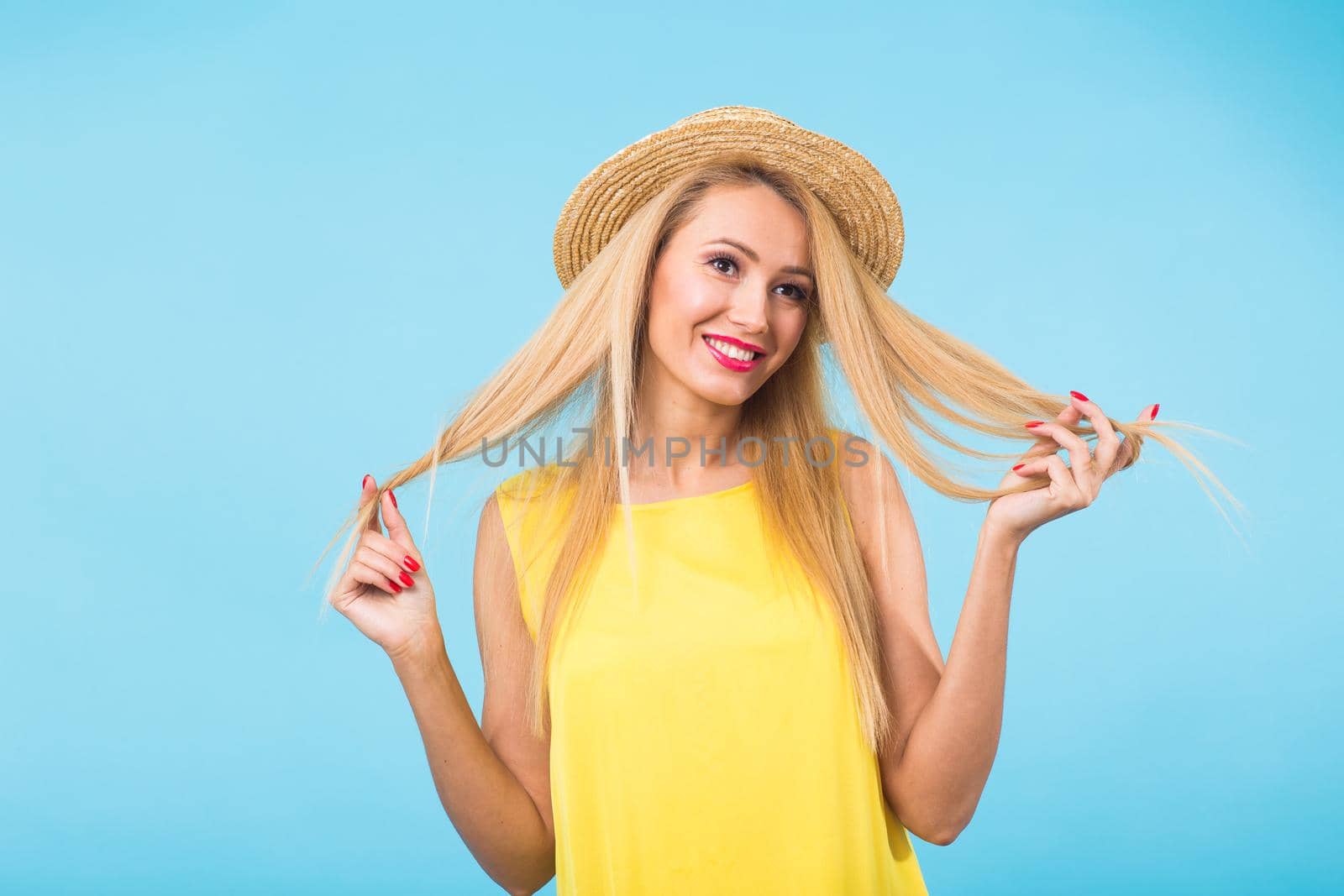 Portrait of smiling blonde woman in fashionable look on blue background. Style, fashion, summer and people concept.