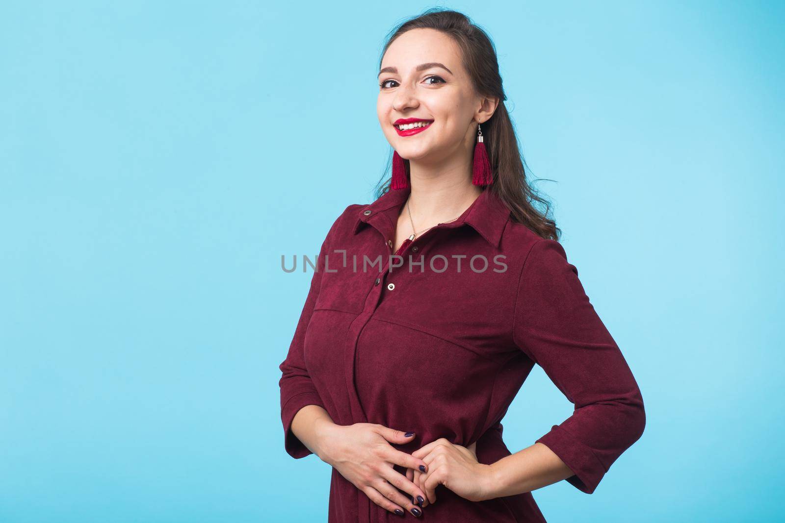 Portrait of young beautiful ginger woman with freckles cheerfuly smiling looking at camera. Isolated on pastel blue background. Copy space.