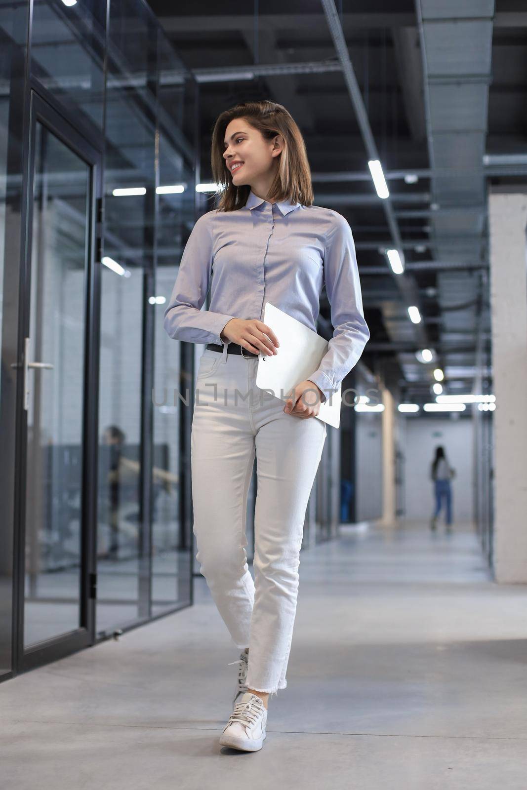 Businesswoman walking along the office corridor with documents. by tsyhun