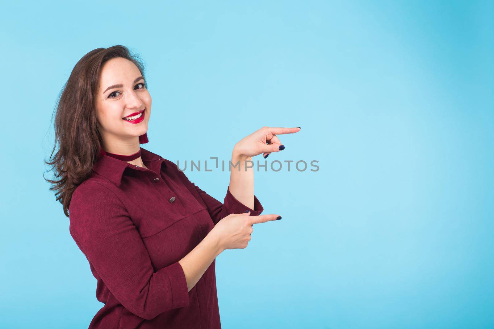 Portrait of young beautiful ginger woman with freckles cheerfuly smiling looking at camera. Isolated on pastel blue background. Copy space.