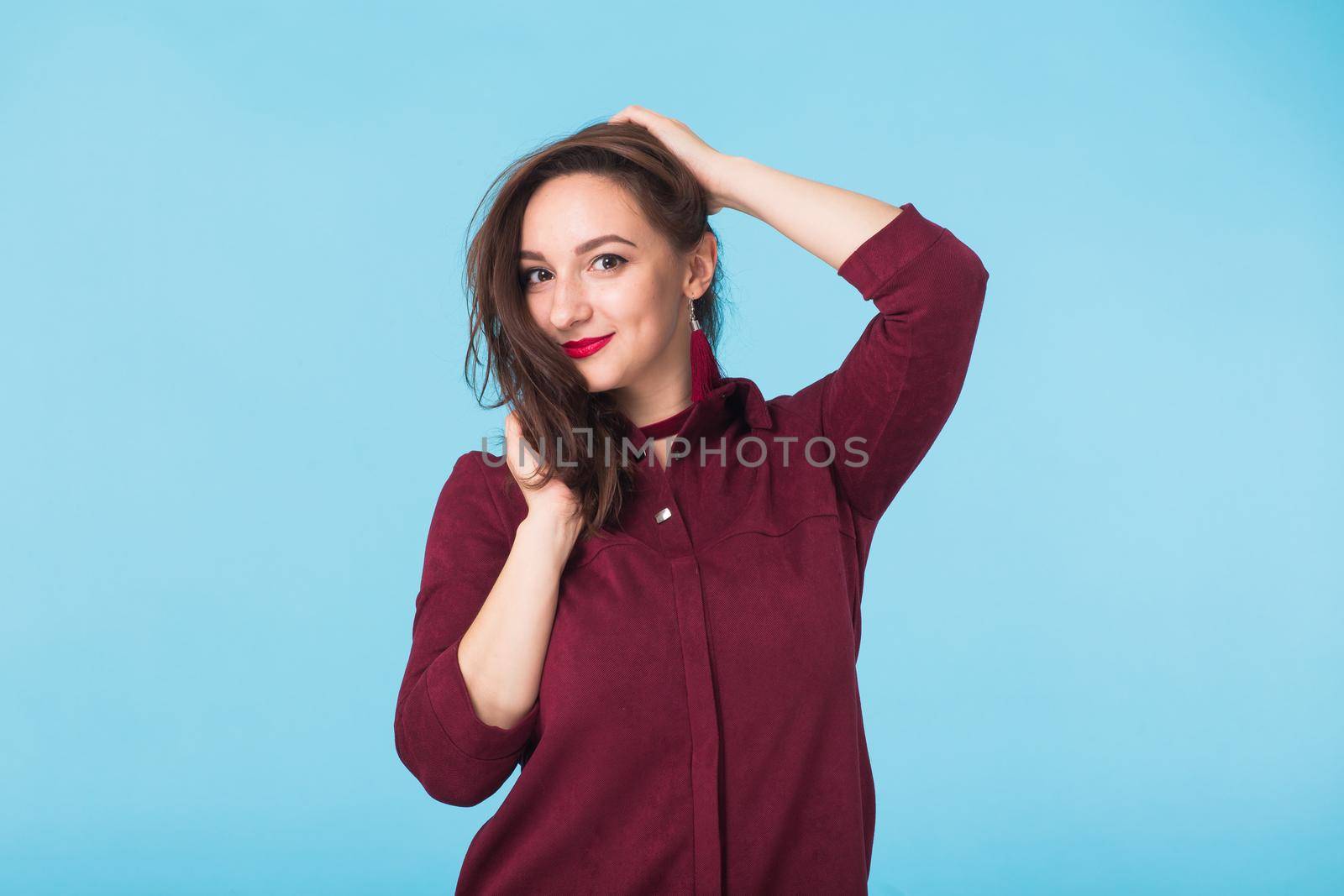 Portrait of young beautiful ginger woman with freckles cheerfuly smiling looking at camera. Isolated on pastel blue background. Copy space.