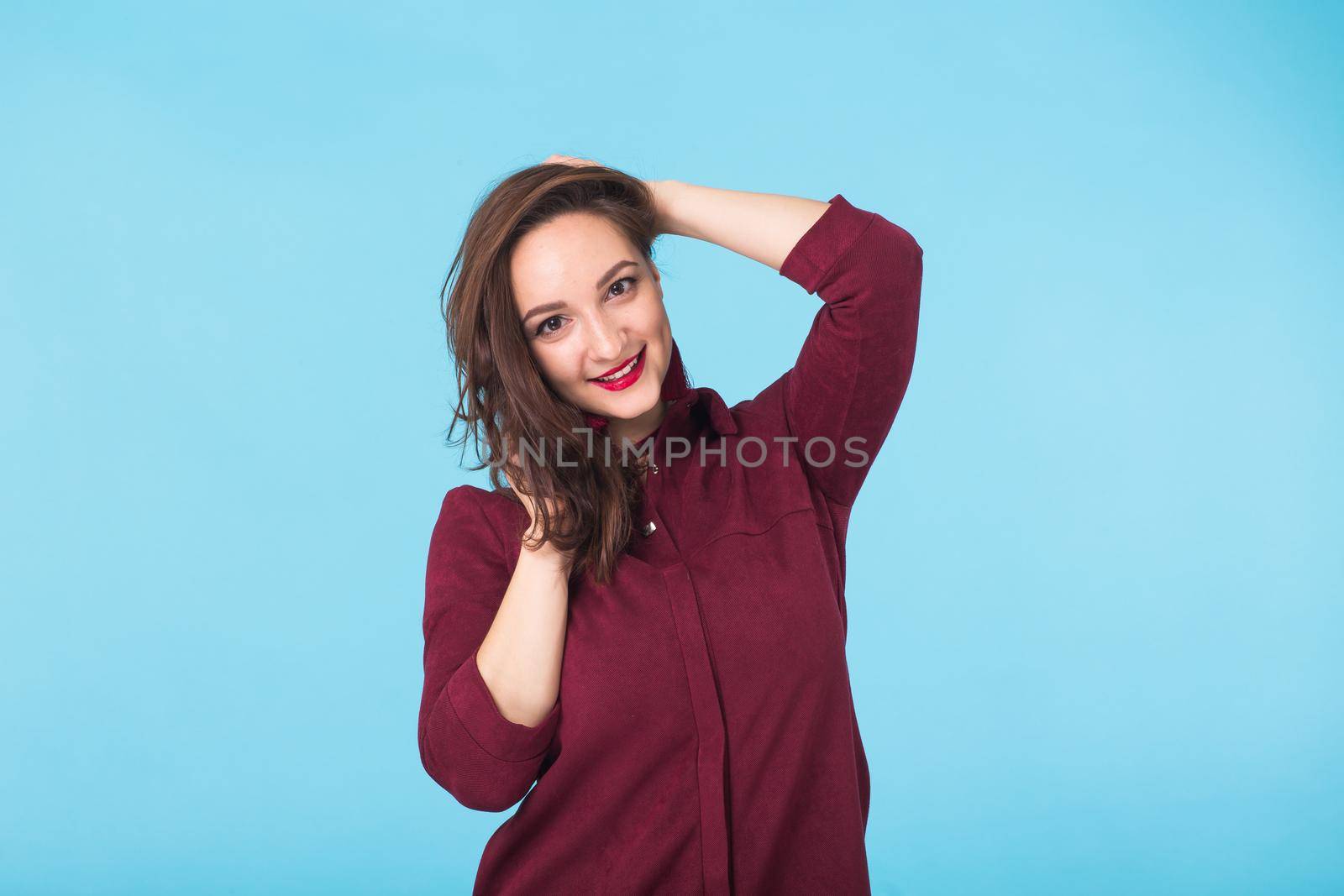 Portrait of young beautiful ginger woman with freckles cheerfuly smiling looking at camera. Isolated on pastel blue background. Copy space.