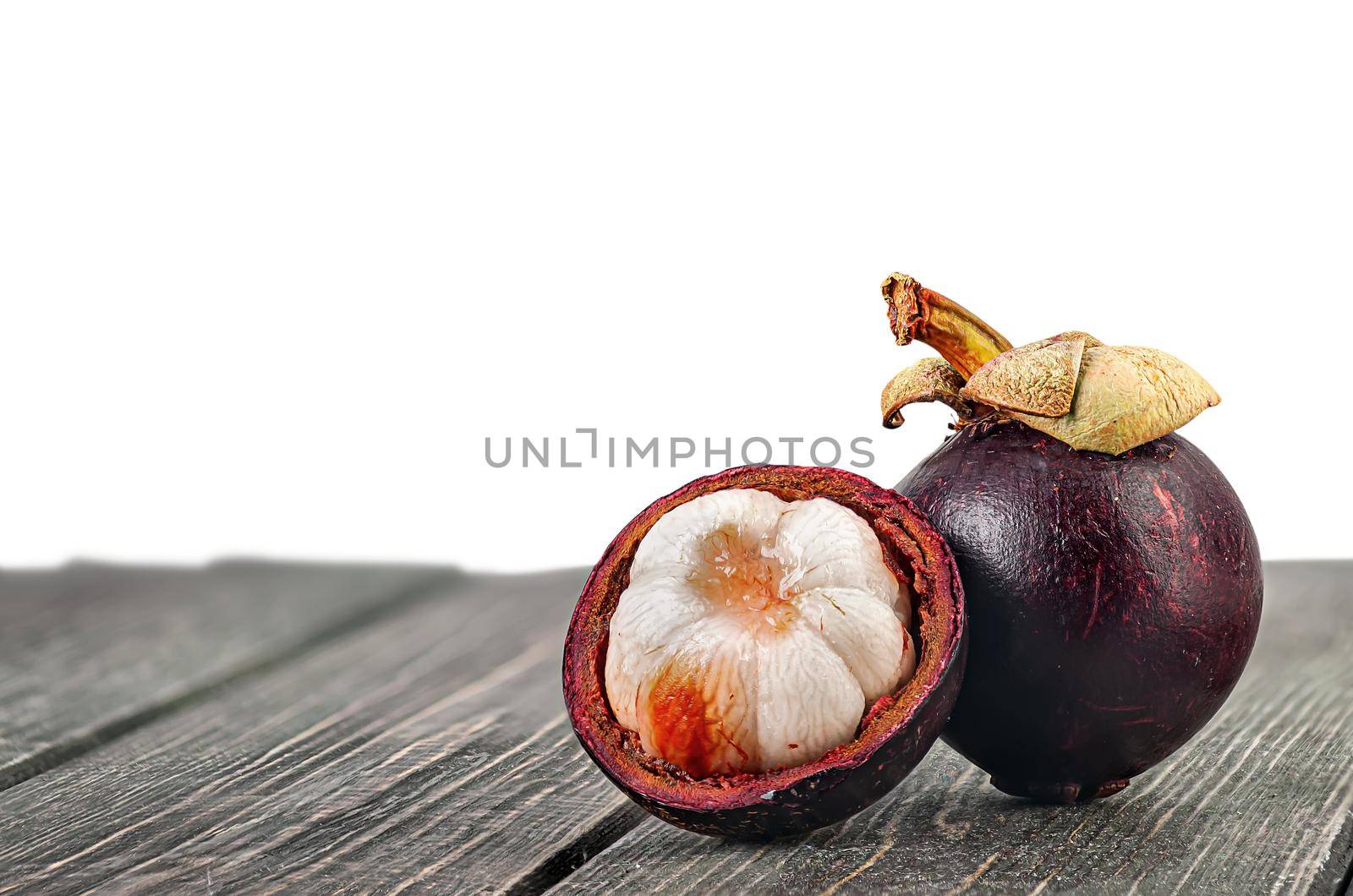 Whole and opened mangosteen on table isolated on white by Cipariss