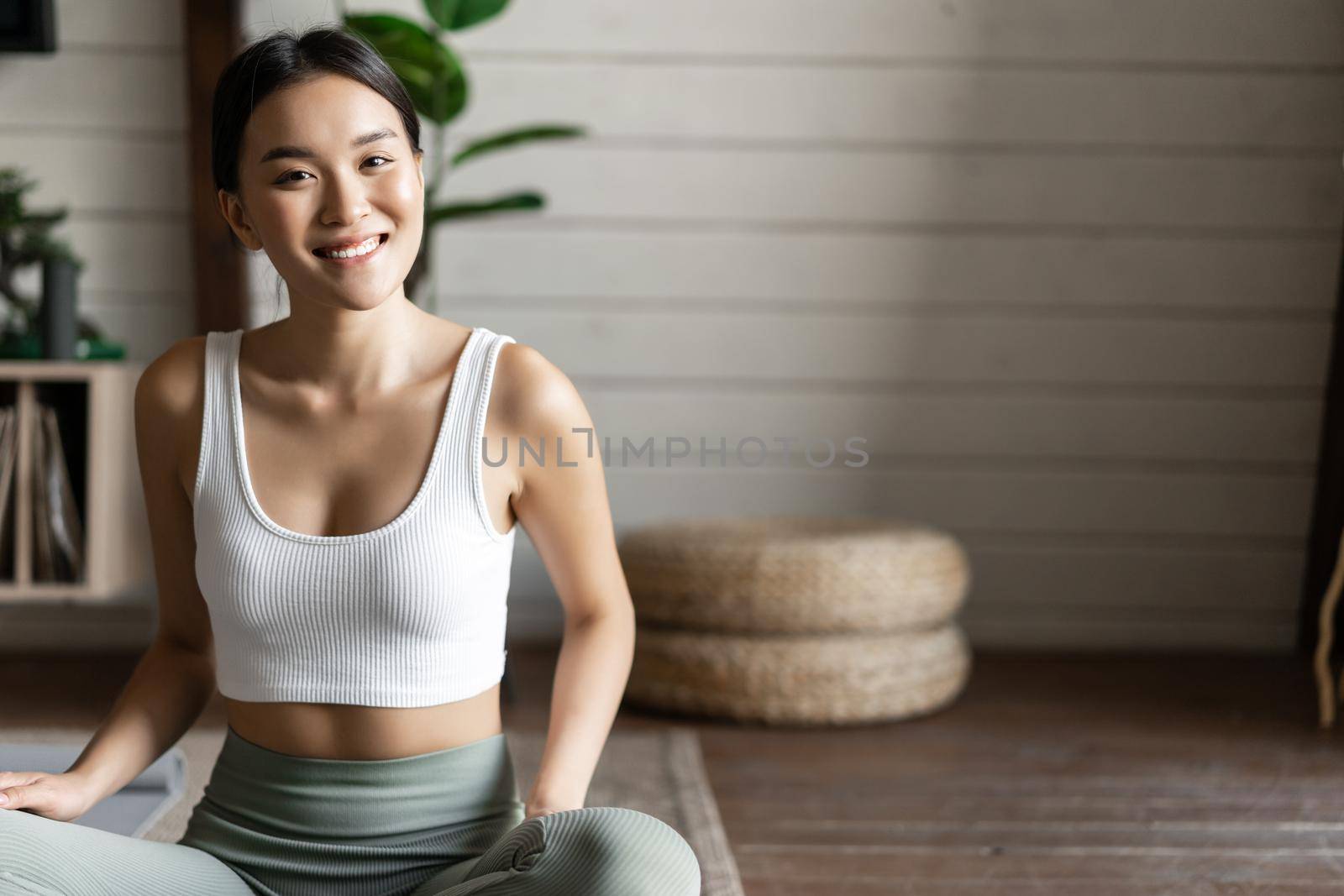 Mindfulness and meditation concept. Young asian woman doing workout at home, yoga meditation in living room on floor mat, getting focused by Benzoix