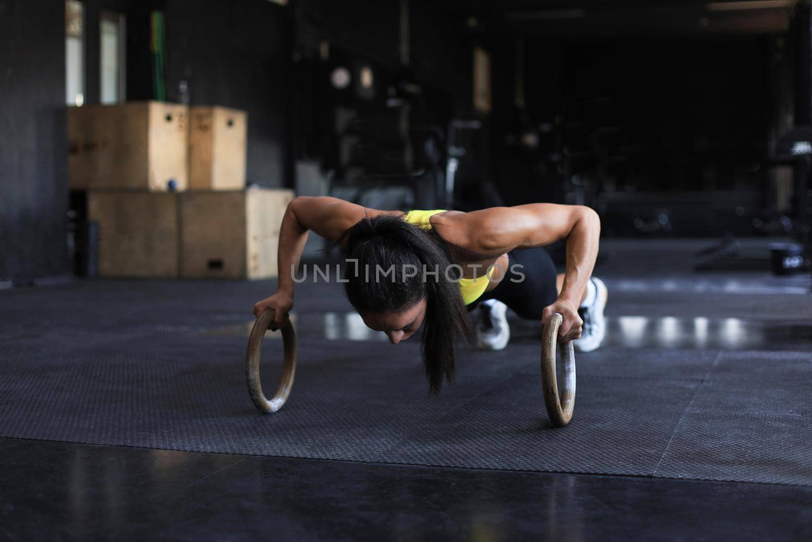 Sporty indian strong woman doing push-ups on rings