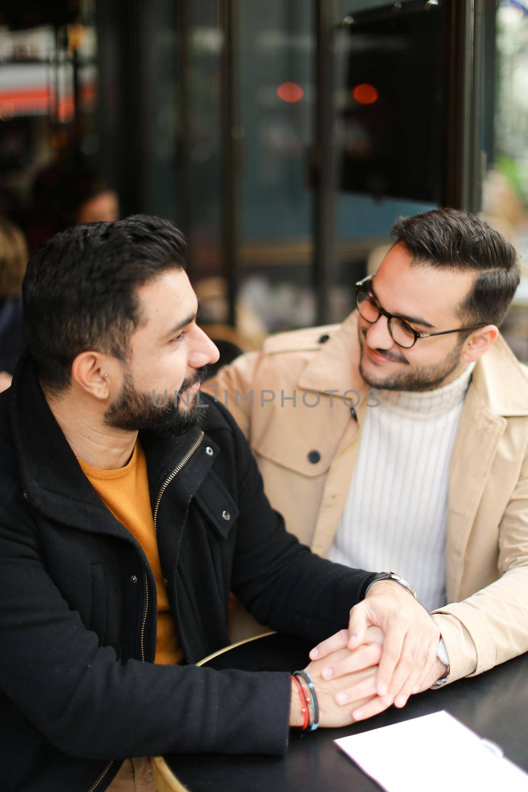 Two cacuasian young gays talking at cafe and holding hands. by sisterspro