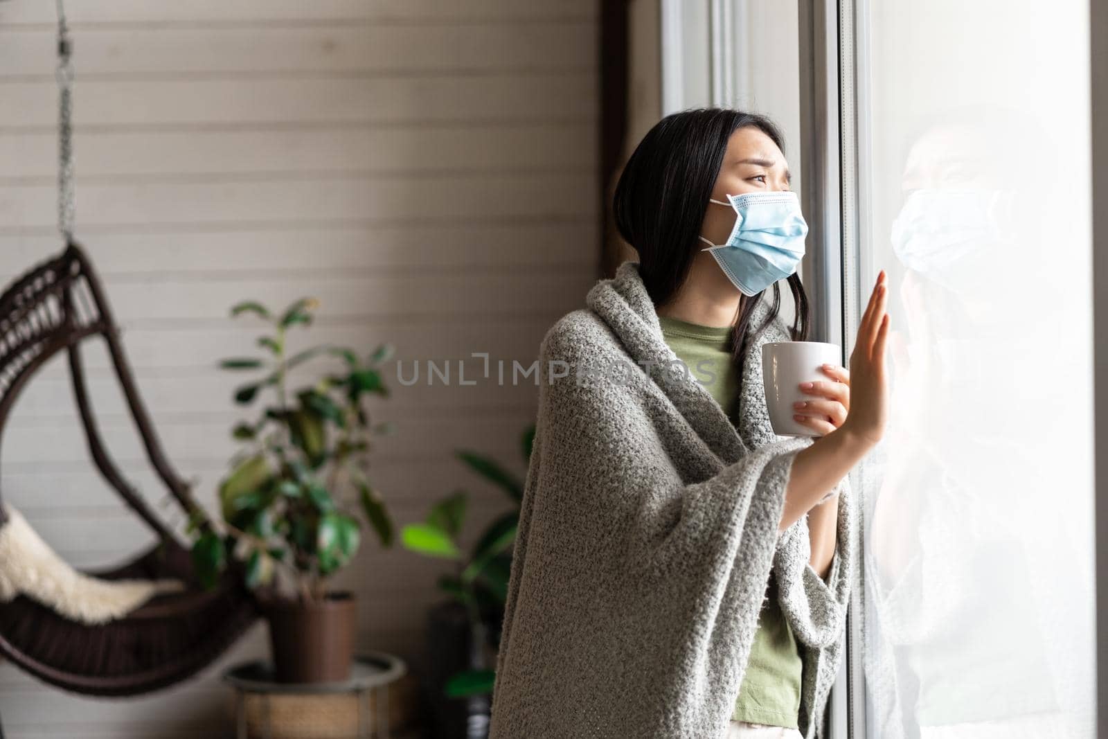 Asian girl in medical face mask, yearning go outside, being sick with covid 19 and staying on self quarantine in her house by Benzoix