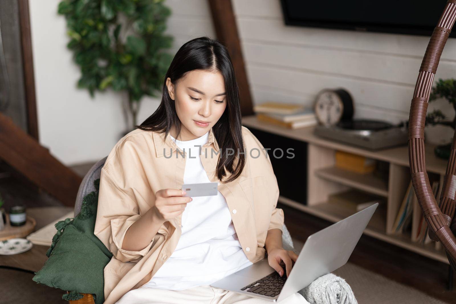 Portrait of korean woman shops online, buying on website with laptop and credit card, purchase course or membership.